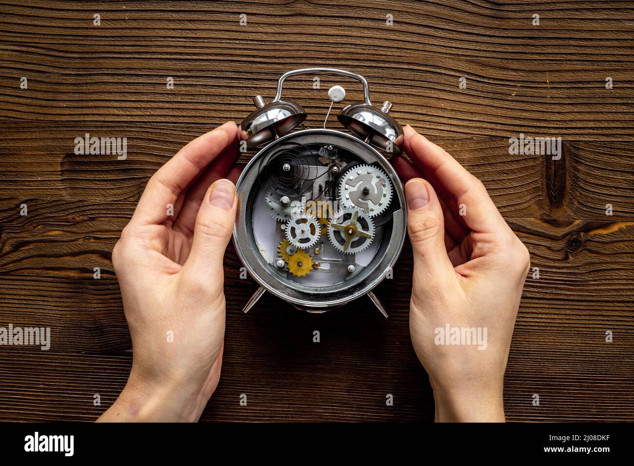 Hands holding alarm clock mechanism with steel gears and wheels close