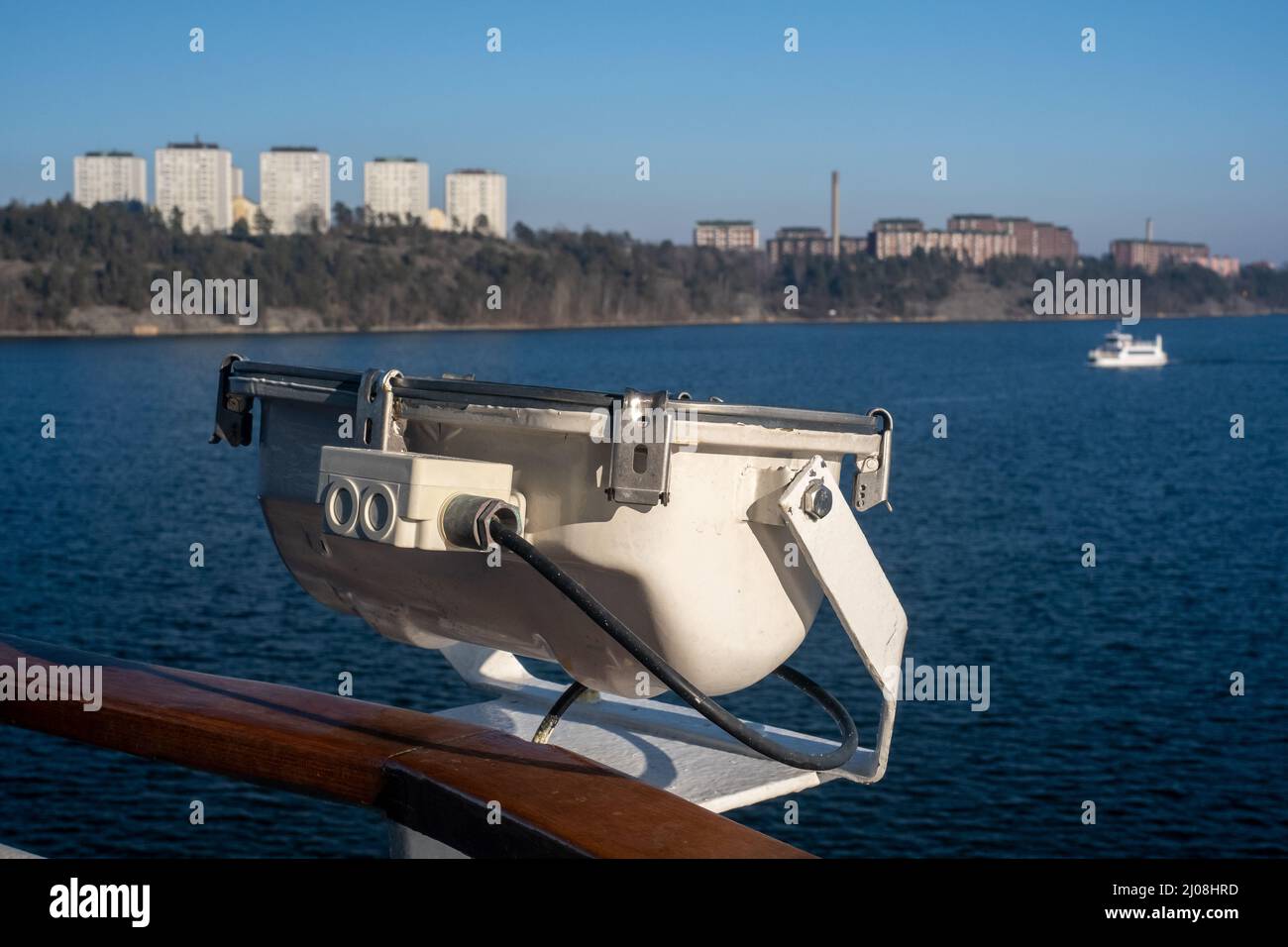 Stockholm / Sweden - MARCH 14, 2022: Closeup of a floodlight attached to a railing with Lidingö residential district in the background. Stock Photo