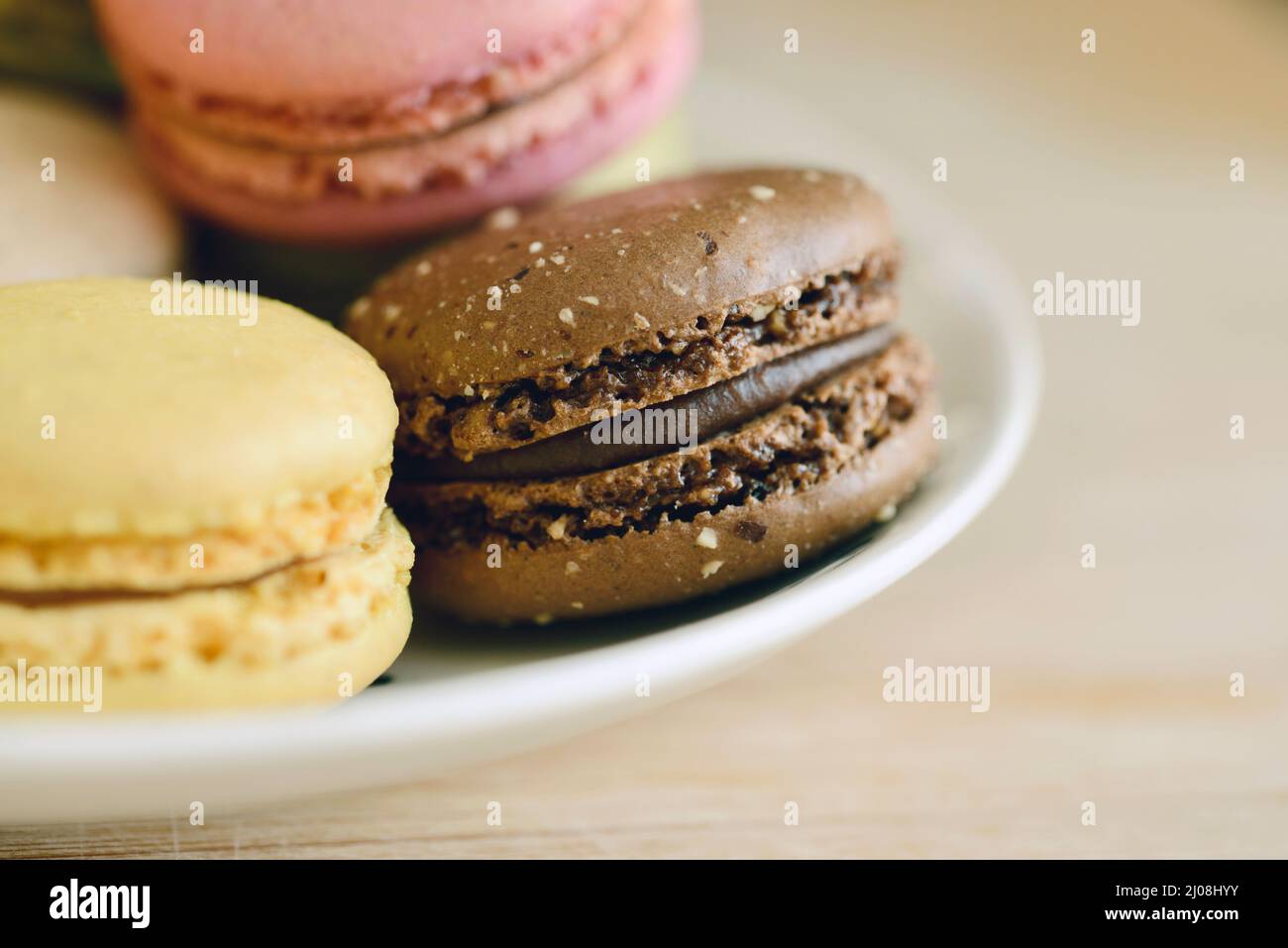 Close up of chocolate, lemon and raspberry macarons on a simple white plate Stock Photo