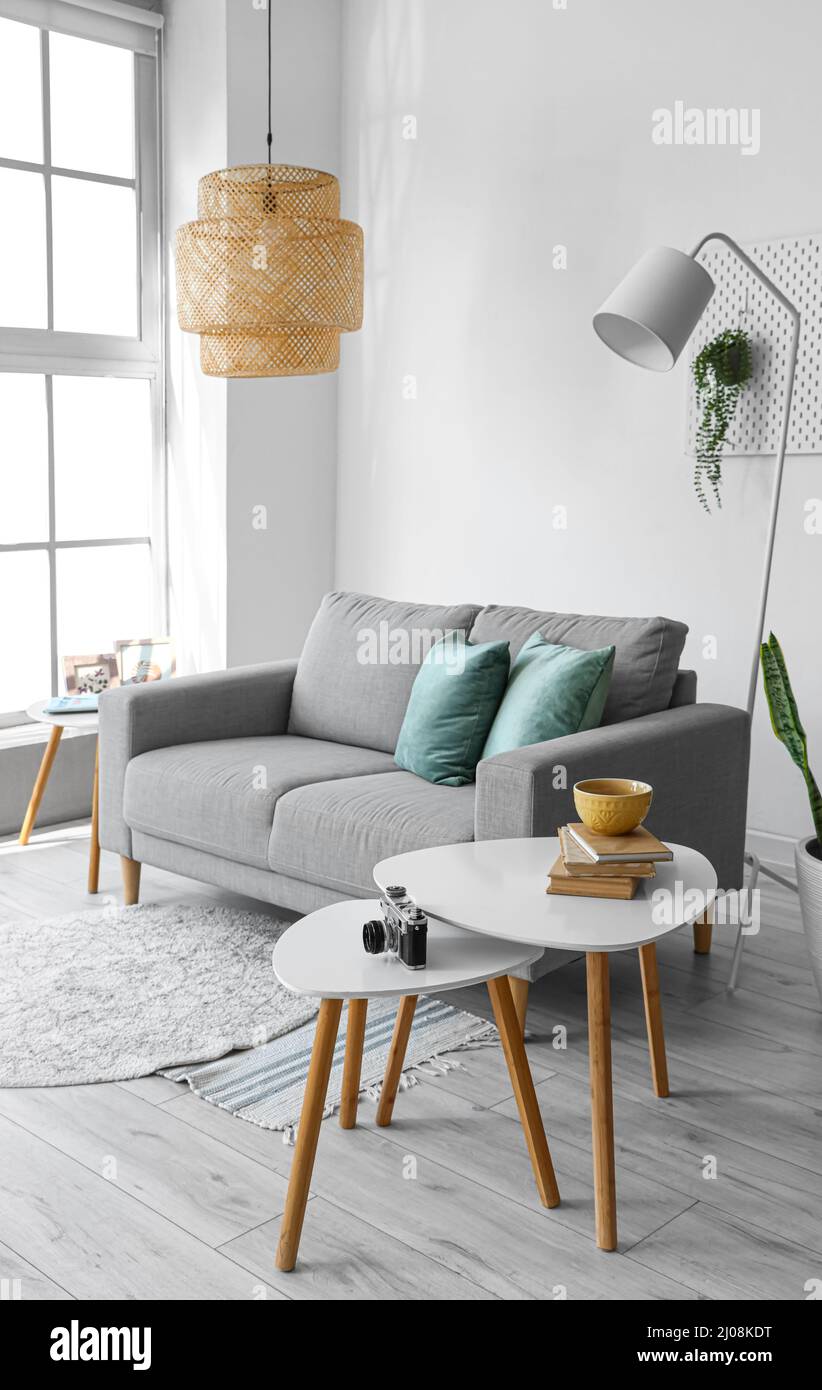 Interior of light living room with grey sofa and tables Stock Photo - Alamy