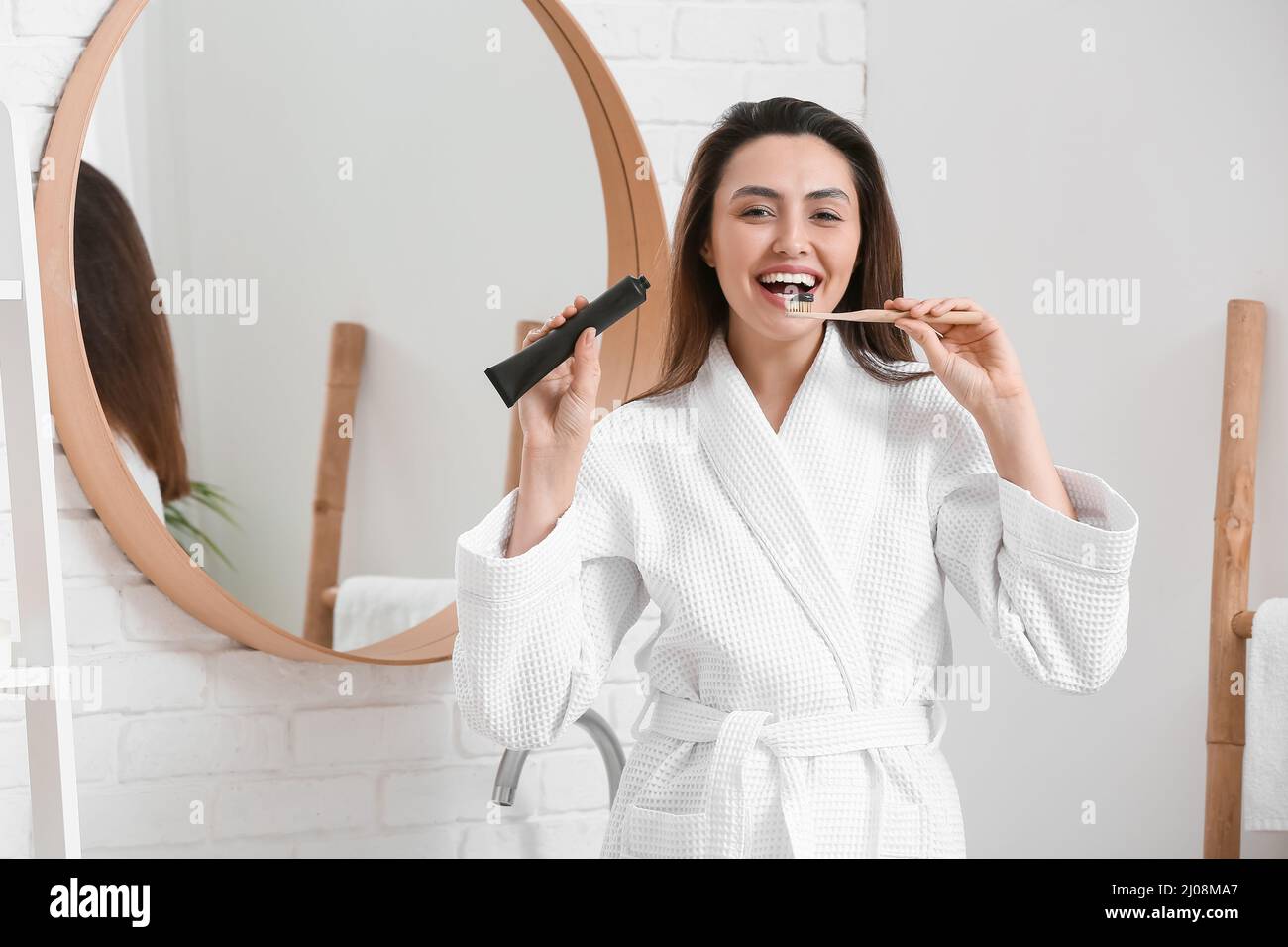 Beautiful young woman brushing teeth with activated charcoal tooth