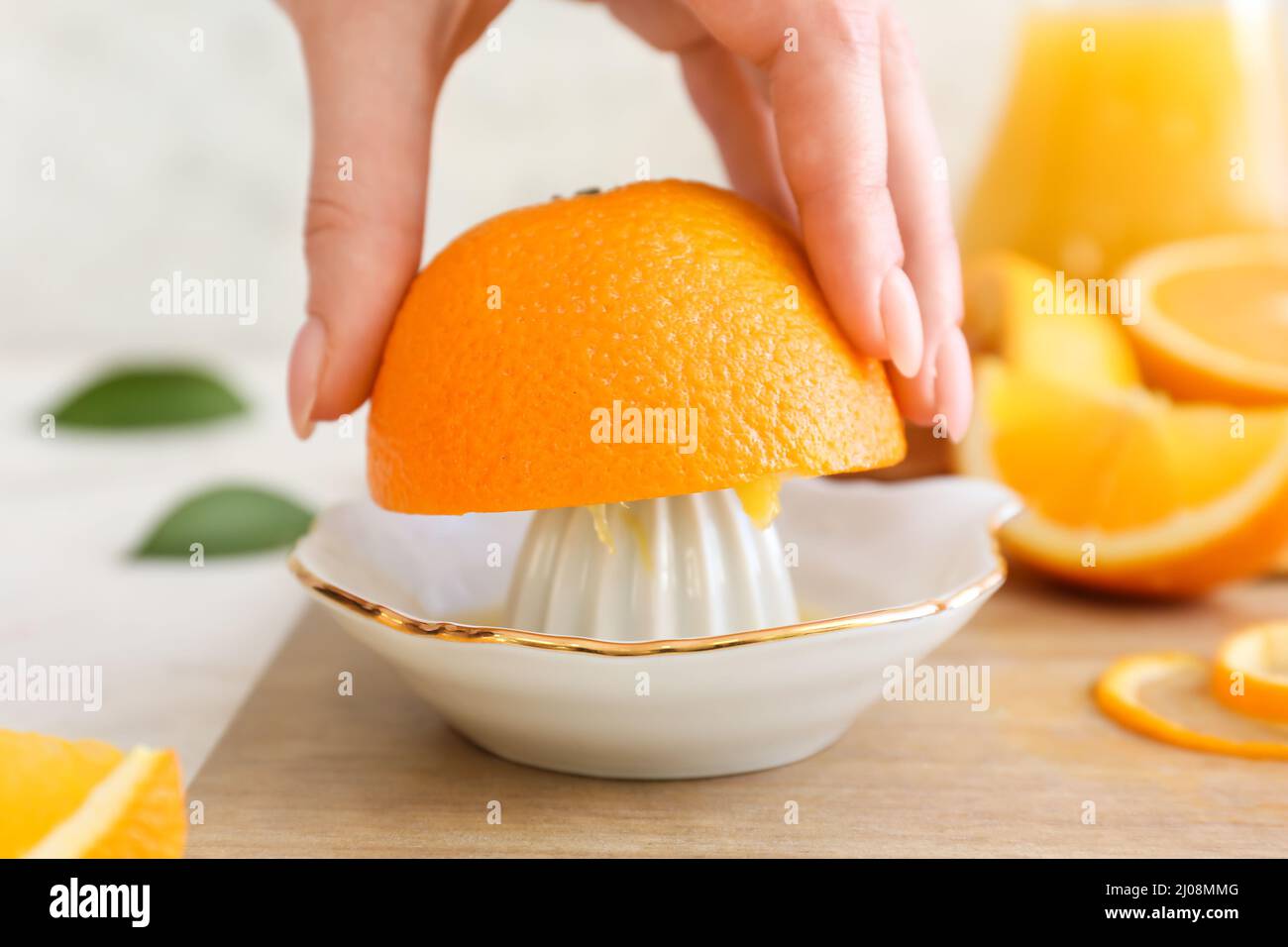 Woman squeezing fresh orange on light background Stock Photo
