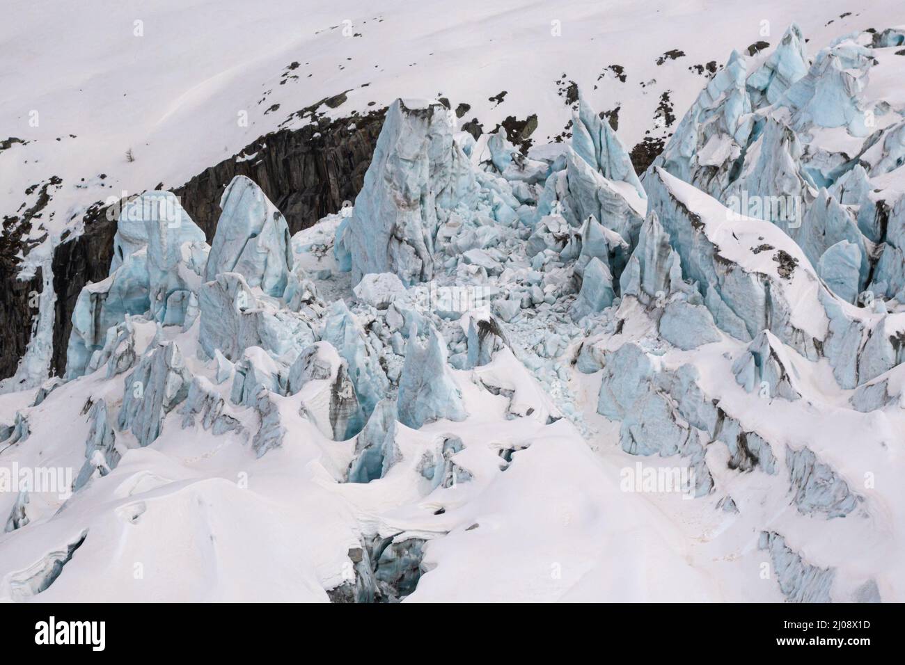 Massive blocks of snow covered ice flowing out of the floor of the receding Argentiere glacier Glacier d'Argentiere with Sahara dust sand form recent Stock Photo
