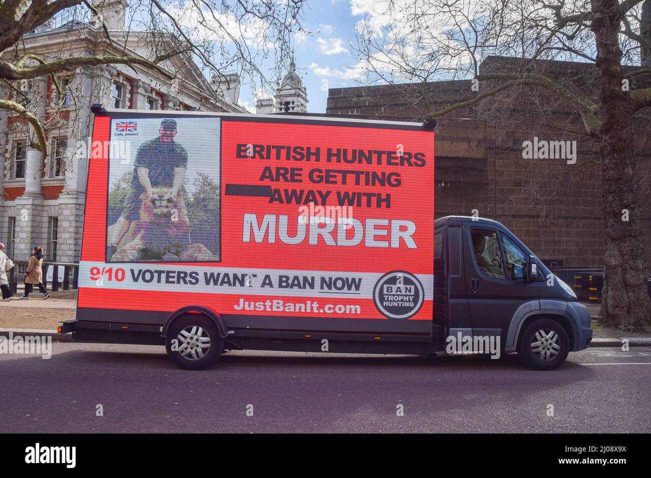 London, UK. 17th March 2022. An ad van passes through Westminster with a digital screen showing an image of a hunter with a dead lion and the words 'British hunters are getting away with murder'. The organisation Campaign to Ban Trophy Hunting is currently running the campaign in response to the UK Government's potential plans to scrap a proposed ban on trophy hunting imports. Credit: Vuk Valcic/Alamy Live News Stock Photo