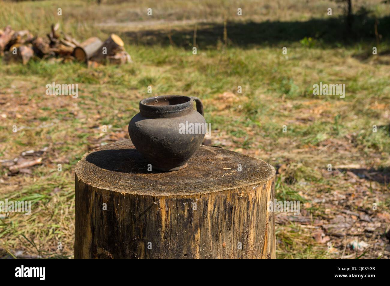 Close view on an ancient  Ukrainian pot standing on a big log  at summer season Stock Photo