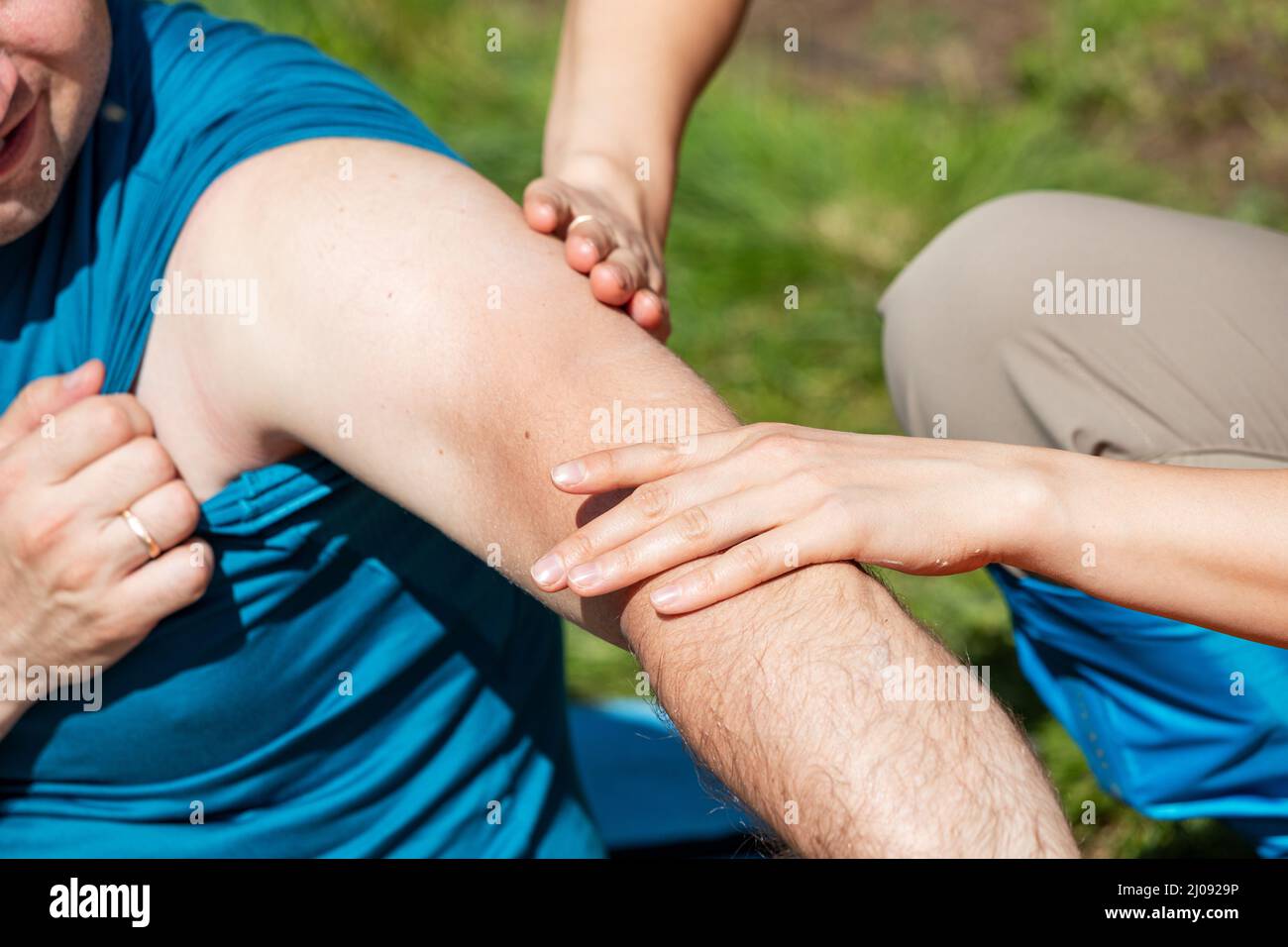 A man on a hike got an injury to the elbow or shoulder joint and his partner does a massage and provides first aid Stock Photo