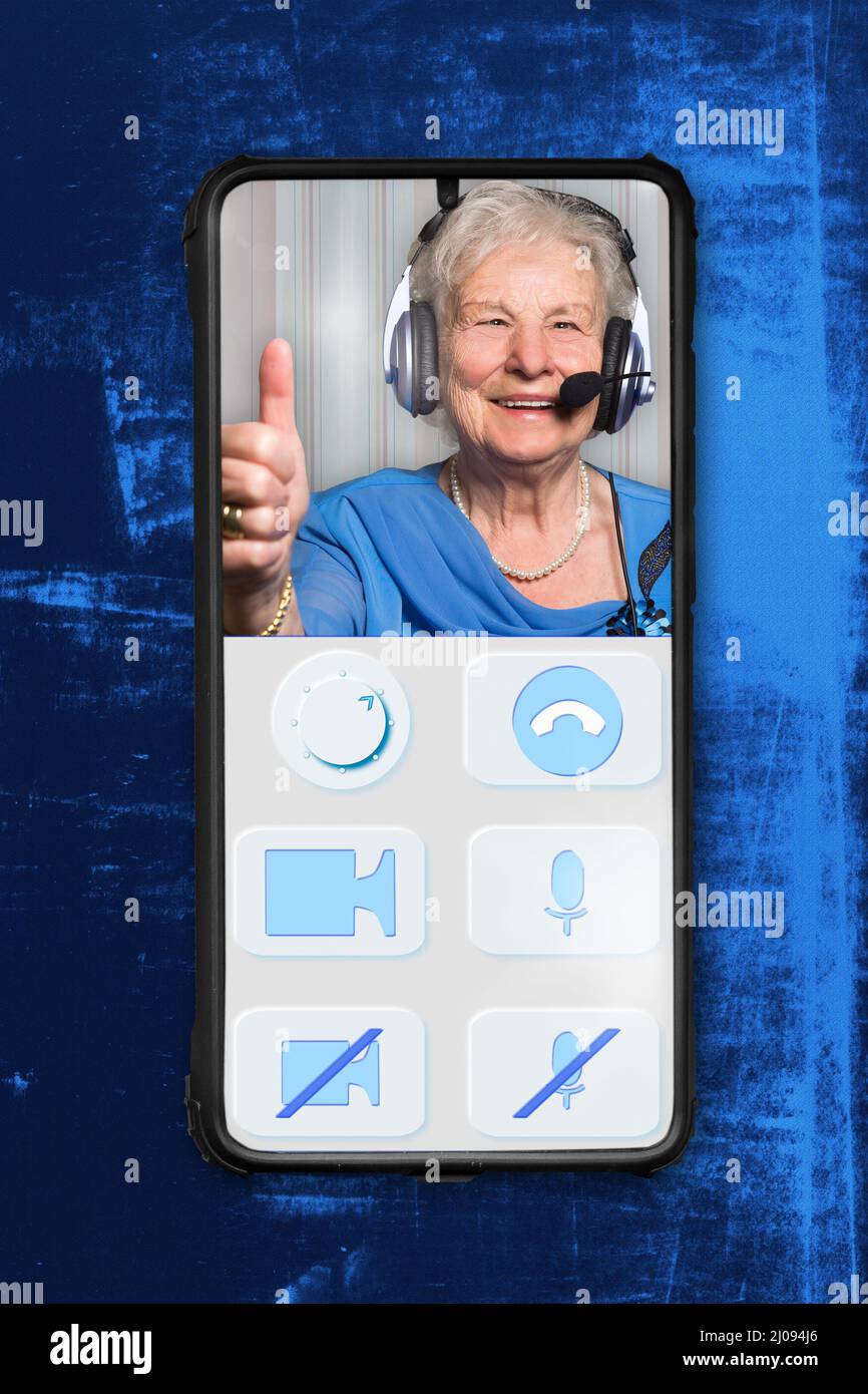 Smartphone shows an imaginary designed app for video calls of elderly people. The buttons are large and clear. On the screen is a cheerful senior citi Stock Photo