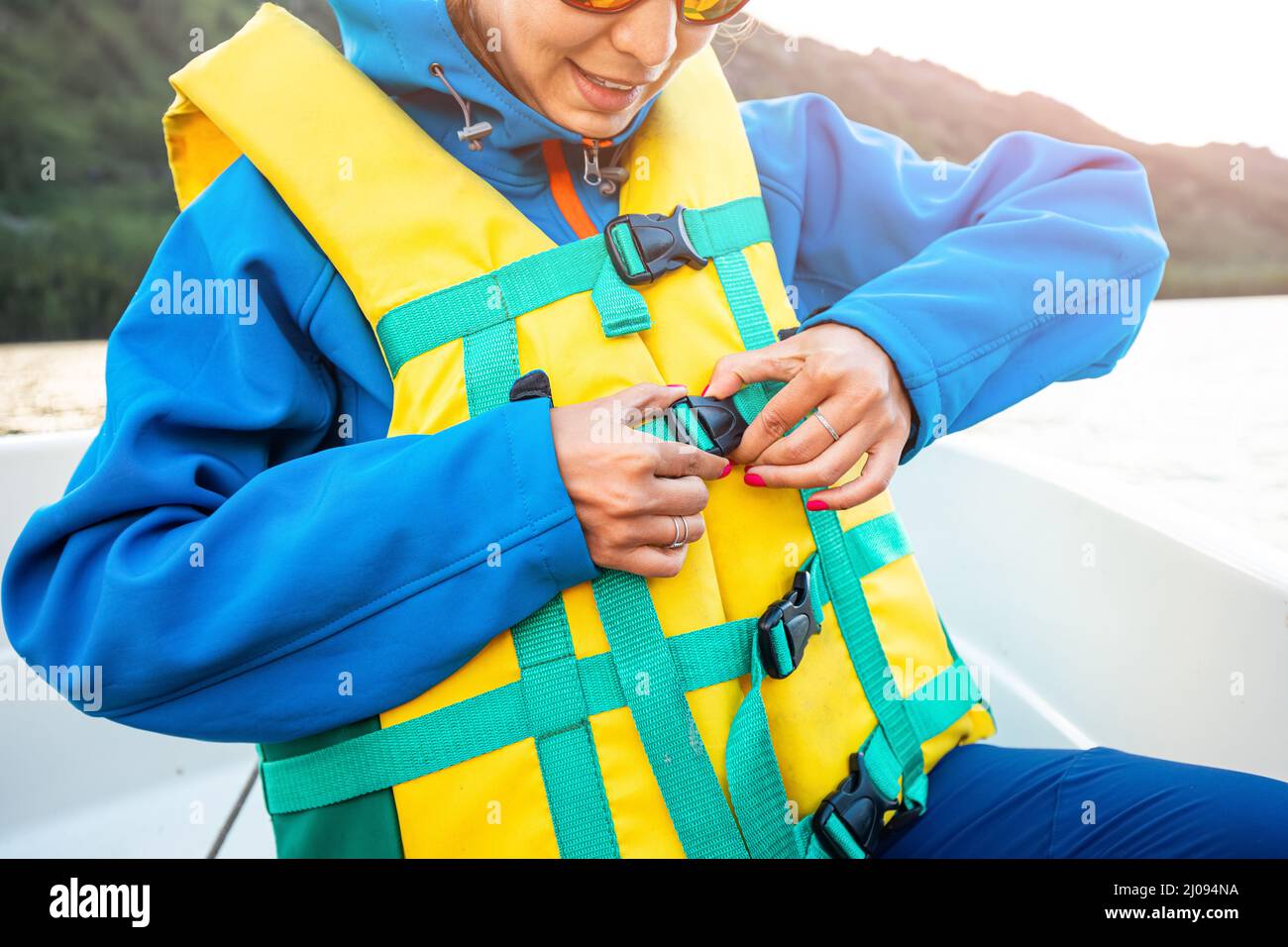 a woman fastens a life jacket while traveling in a boat. Safety and emergency concept Stock