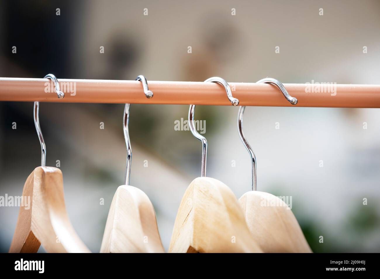 Earth color coat rack with wooden hangers and chromed metal hooks Stock Photo