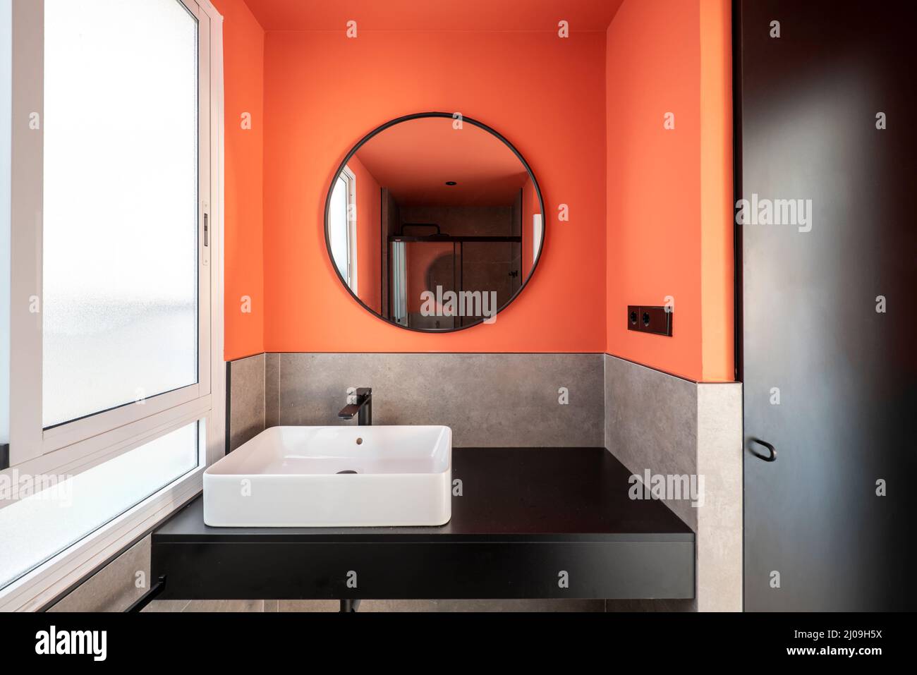 Bathroom with a white porcelain sink on a black wooden countertop, a  walk-in shower and a round mirror with a black frame to match the  accessories nex Stock Photo - Alamy, image size:1300x957
