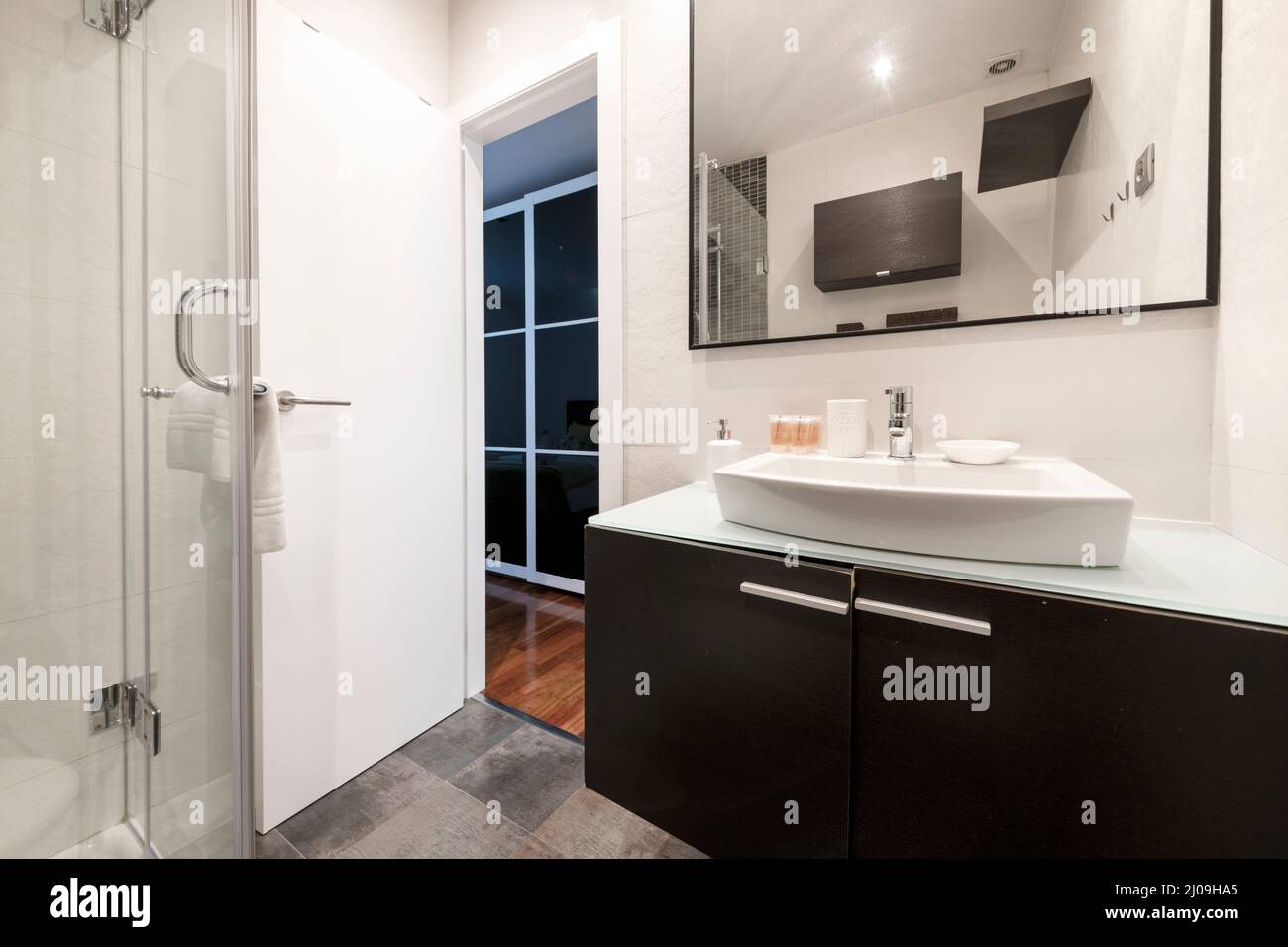 Bathroom with glass-enclosed shower stall, angular white porcelain sink ...