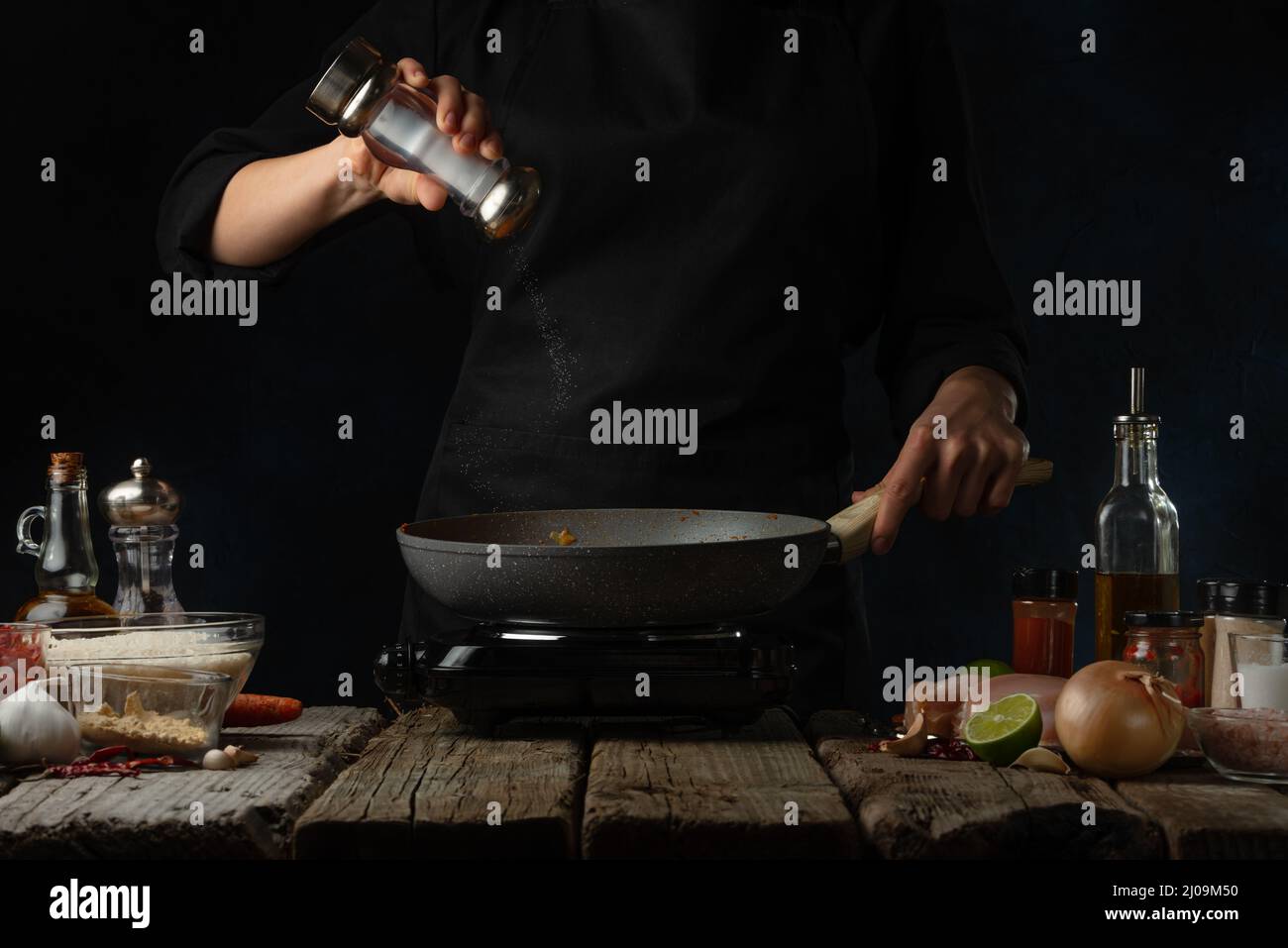 Professional chef salts frying chicken fillet. Backstage of cooking
