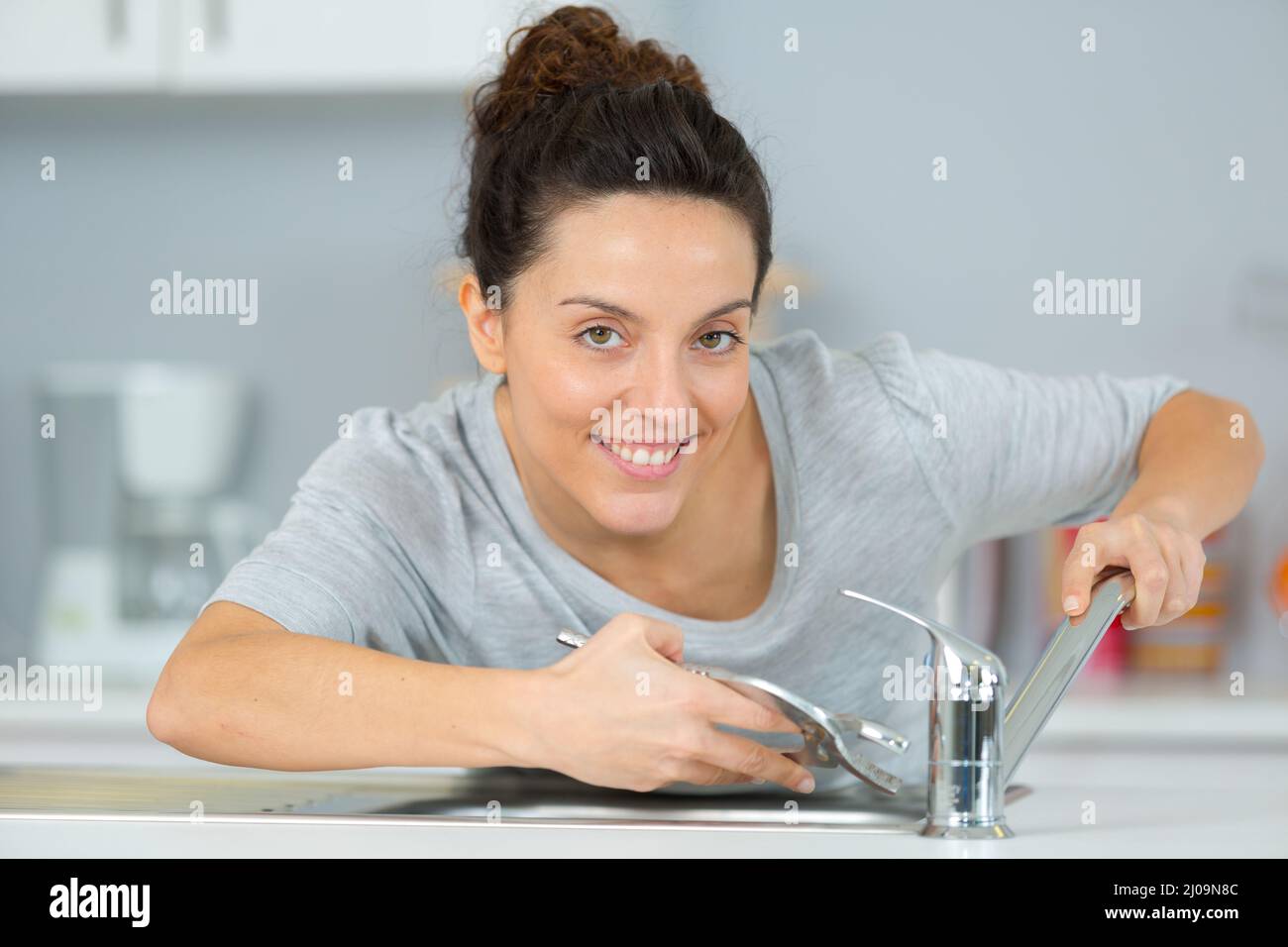 female trainee plumber working on tap Stock Photo