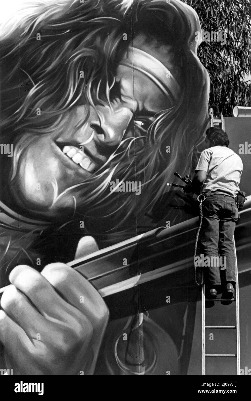 Billboard painter touching up  the face of Ted Nugent on a giant Sunset Strip billboard promoting the release of a new record album circa 1979, Los Angeles, CA Stock Photo