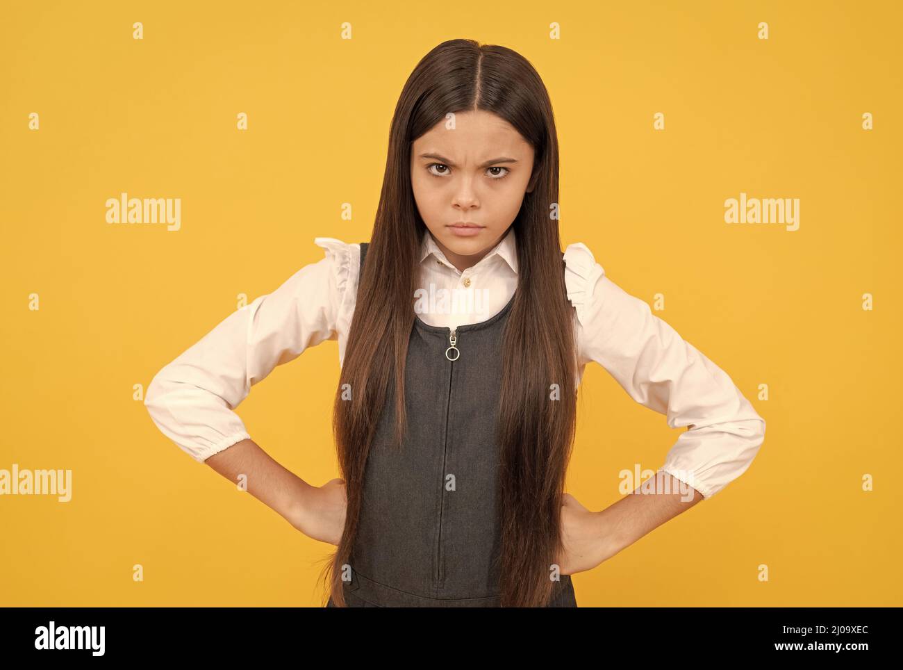 Becoming disobedient. Disobedient child yellow background. Frown girl stand with arms akimbo Stock Photo