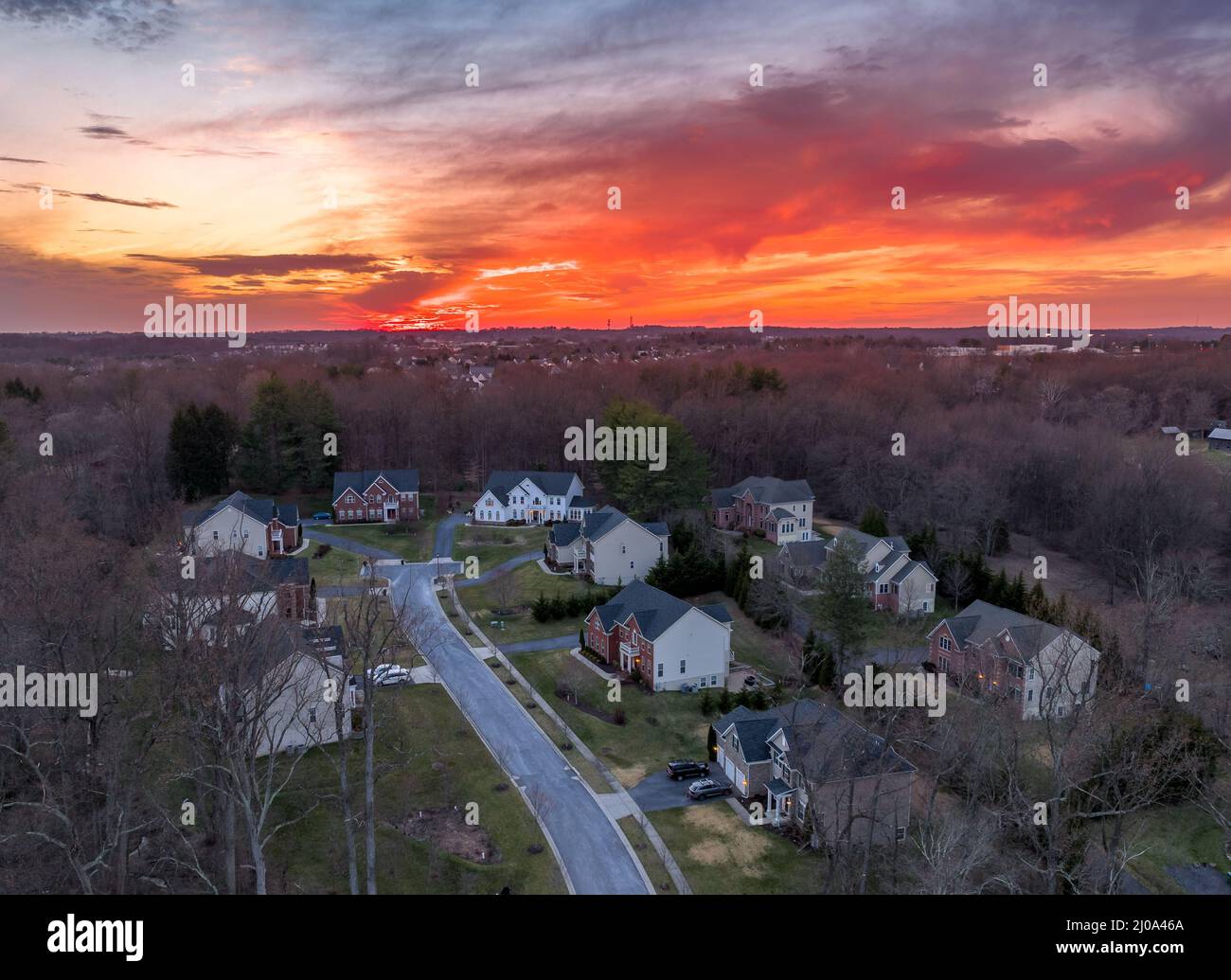 Curving road leading to a dead end neighborhood with colorful orange evening sun is setting over upper class East Coast American neighborhood cul-de-s Stock Photo