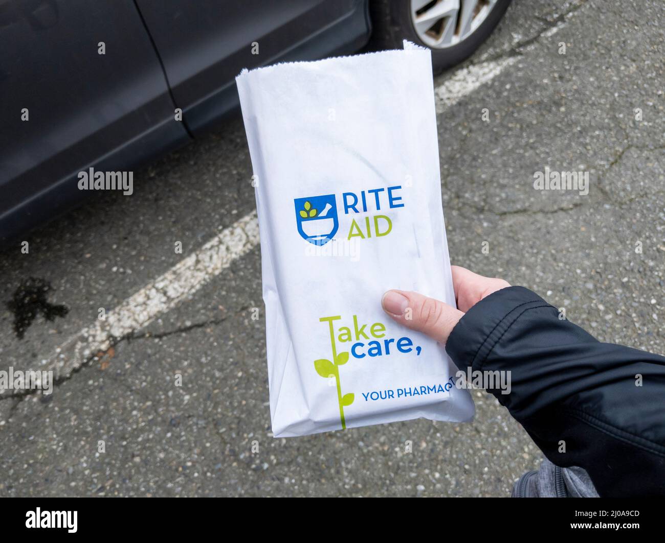 Lynnwood, WA USA - circa March 2022: Angled view of a woman holding a white paper Rite Aid bag, with a prescription inside Stock Photo