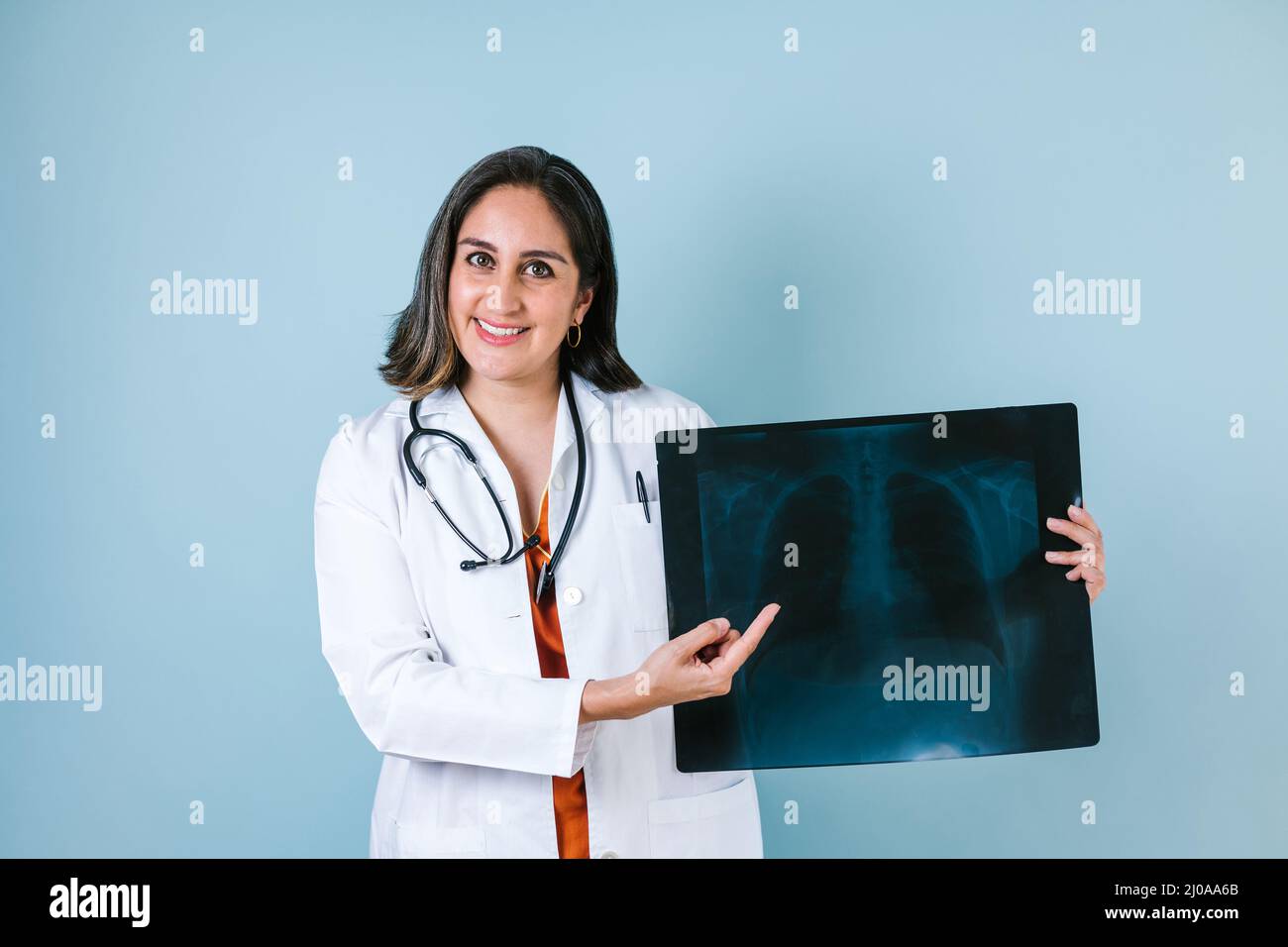 hispanic woman doctor looks at xray radiography images in radiology clinic on blue background in Mexico Latin America Stock Photo