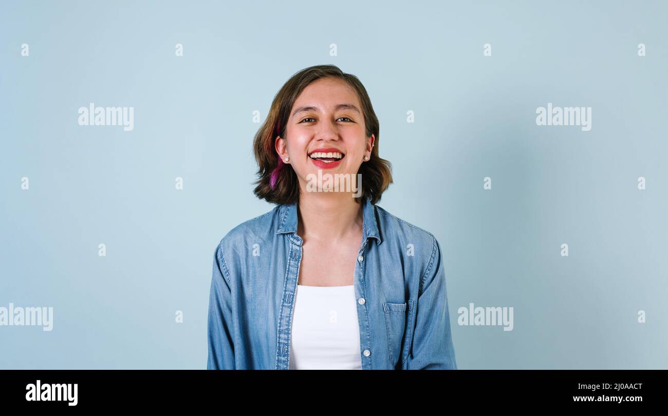 Portrait of hispanic girl smiling looking at camera on blue background in Mexico Latin America Stock Photo