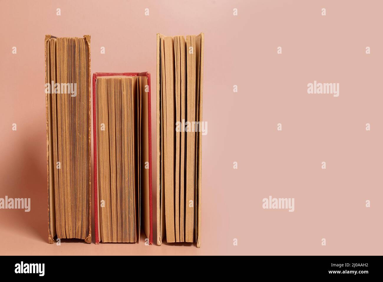 A stack of old worn books on a colored background Stock Photo