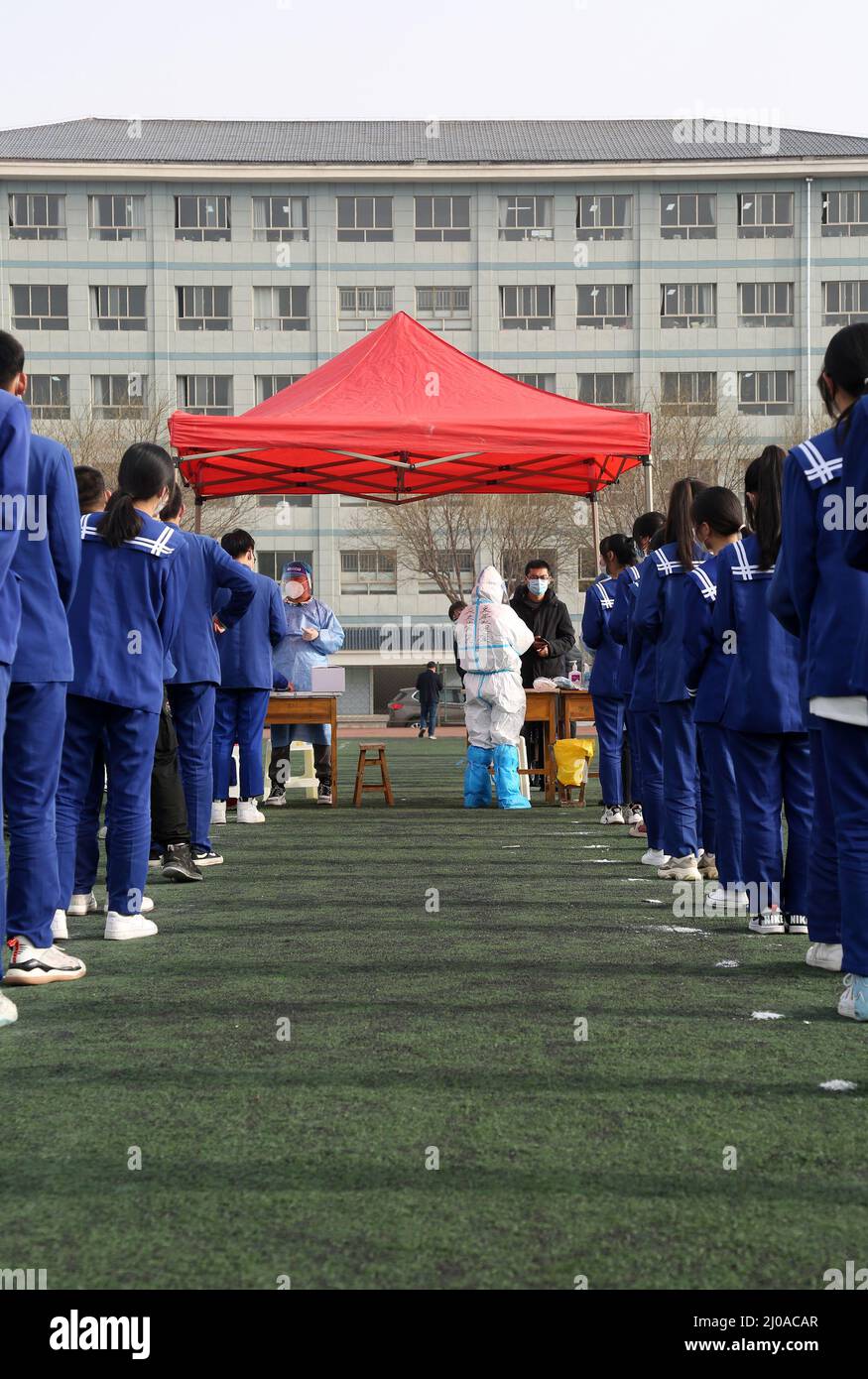 PINGLIANG, CHINA - MARCH 18, 2022 - Teachers and students line up at the stadium for nucleic acid sampling at No. 5 Middle School in Pingliang City, N Stock Photo