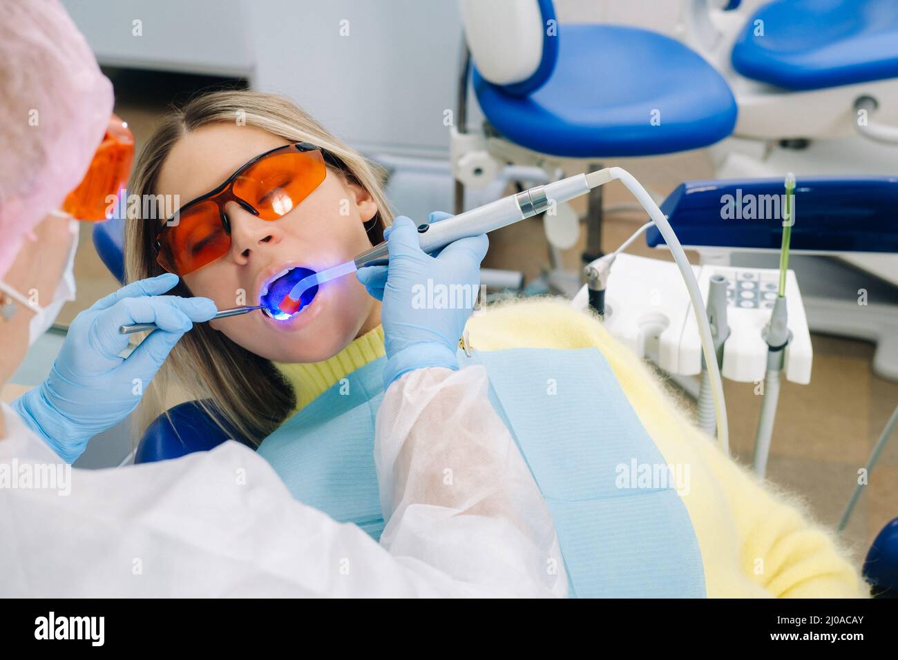 A female patient in dental glasses treats teeth at the dentist with