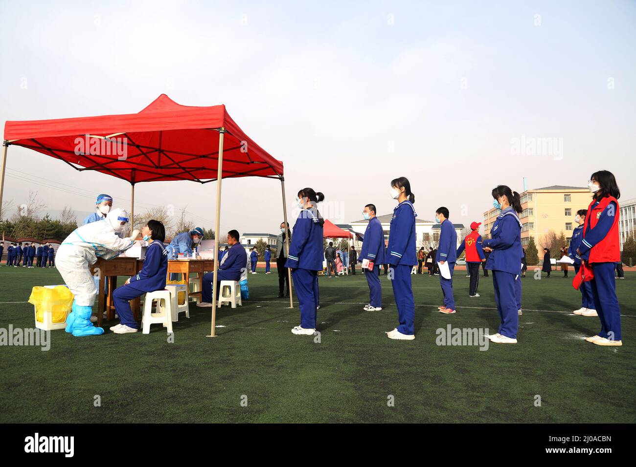 PINGLIANG, CHINA - MARCH 18, 2022 - Teachers and students line up at the stadium for nucleic acid sampling at No. 5 Middle School in Pingliang City, N Stock Photo