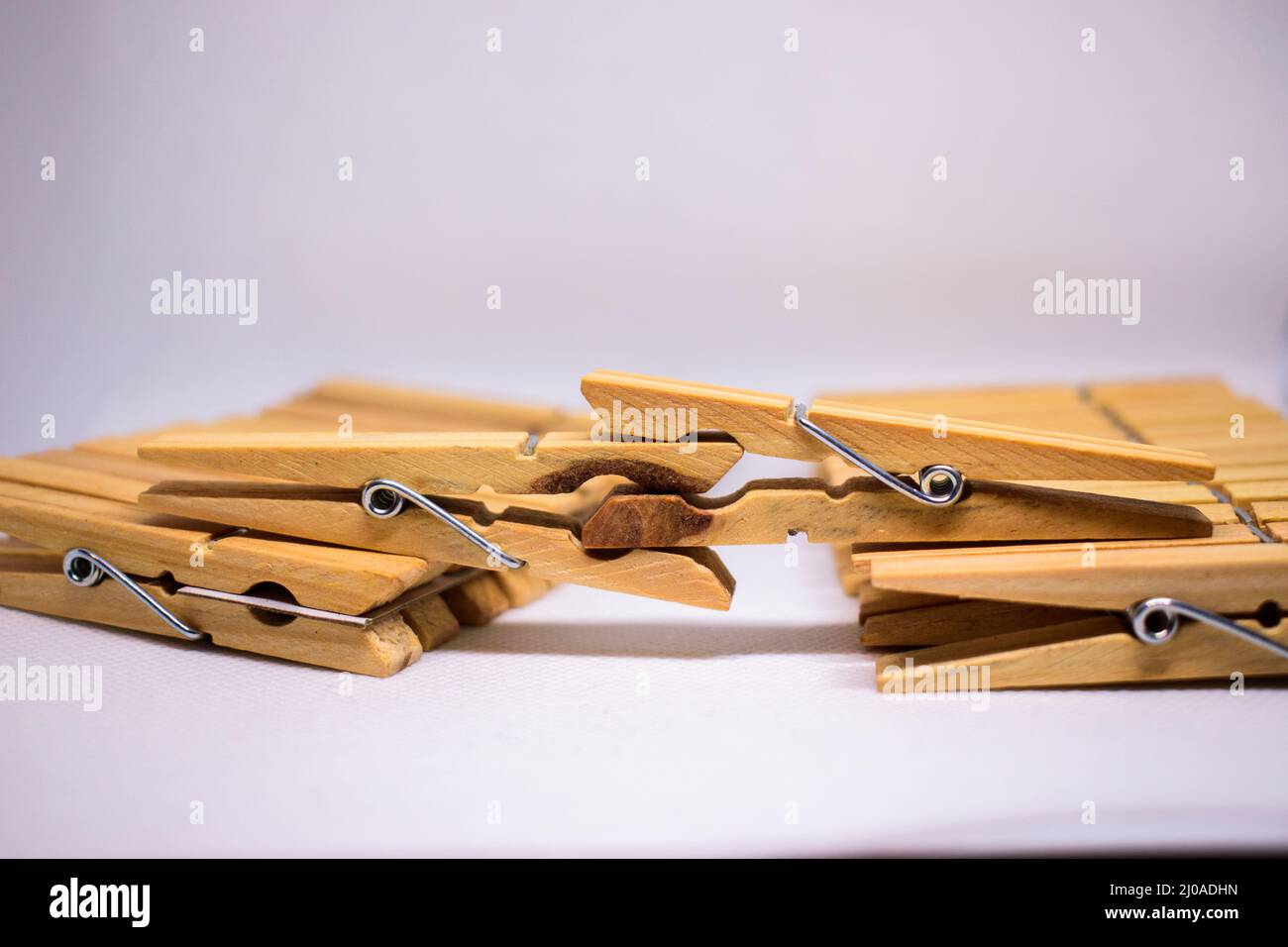 https://c8.alamy.com/comp/2J0ADHN/closeup-shot-of-the-wooden-clothes-pegs-attached-to-each-other-on-the-white-background-2J0ADHN.jpg