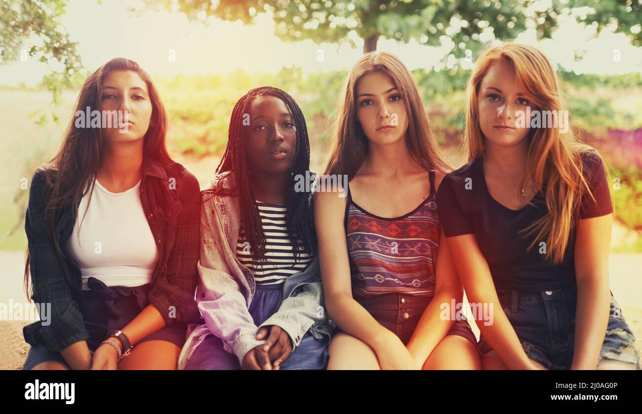 So far they werent that amused.... A group of displeased looking teenage girls sitting outdoors. Stock Photo