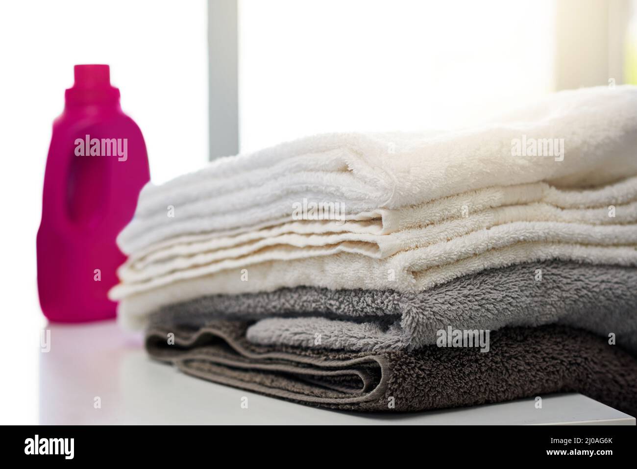 Clean and fresh. Shot of a bottle of detergent alongside a pile of folded towels at home Stock
