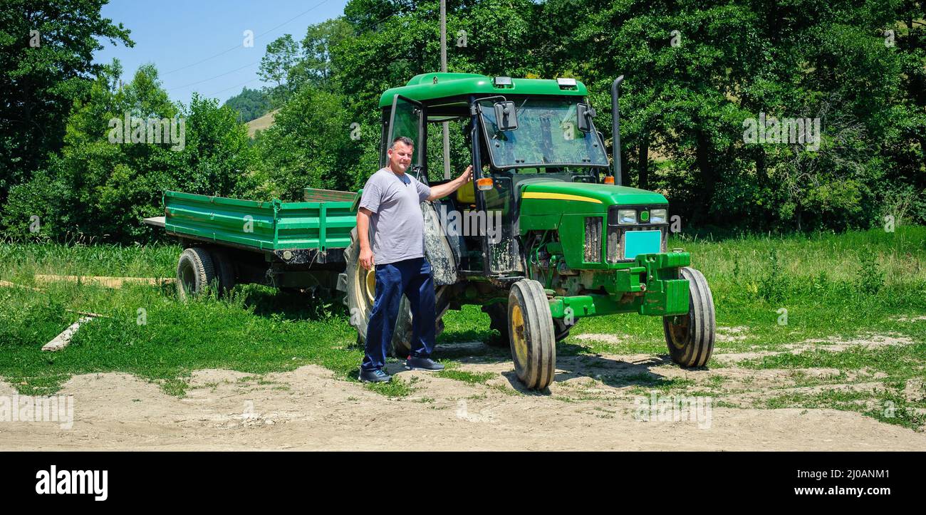Proud farmer standing in front of tractor. Montenegro Stock Photo - Alamy