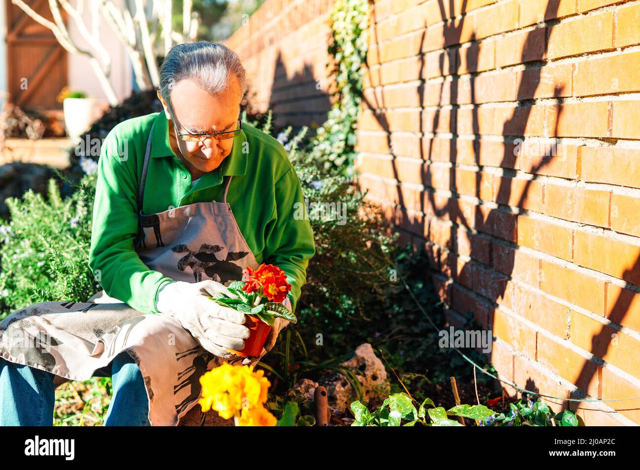 older man relaxing, while tending to his garden Stock Photo