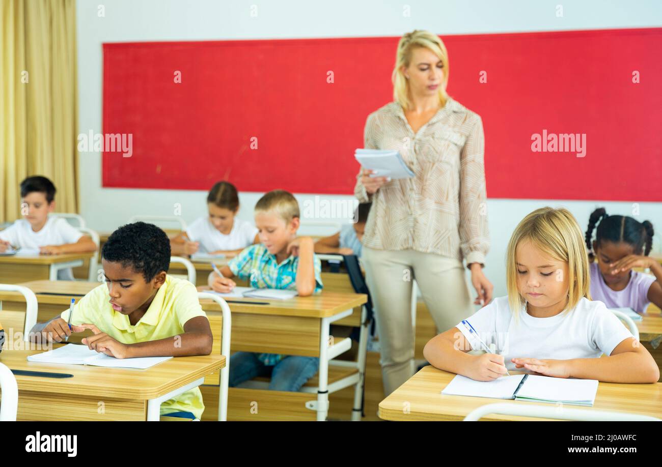 Teacher and pupils working in classroom at elementary school Stock ...
