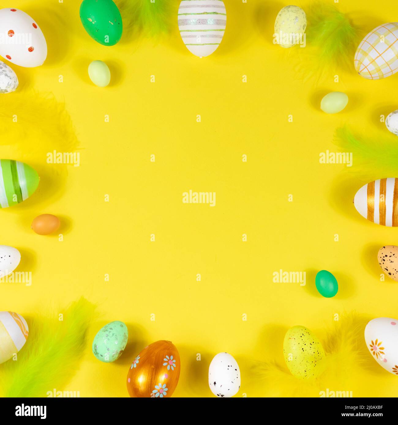 Easter frame with eggs and feathers on a yellow background. View from above. Card with copy space for text. Stock Photo