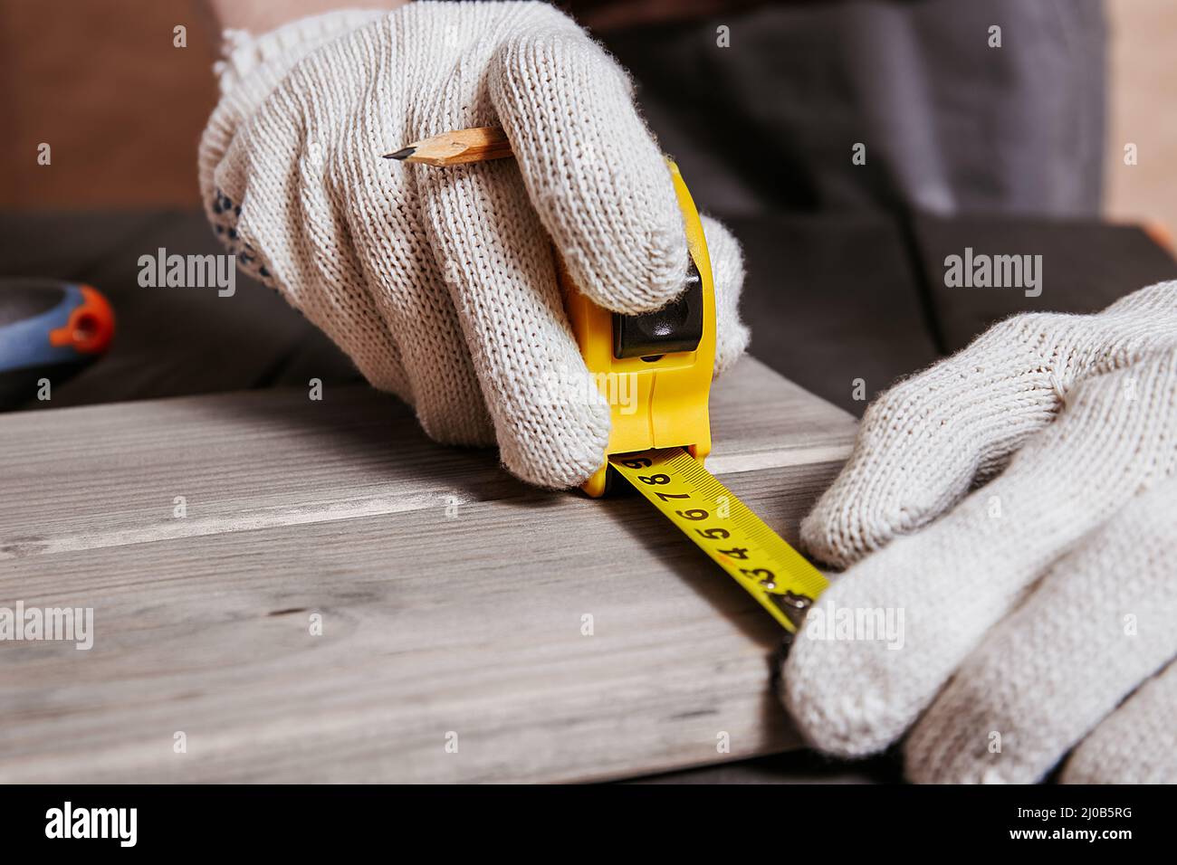 Carpenter is measuring length of wood planks or timbers by measuring