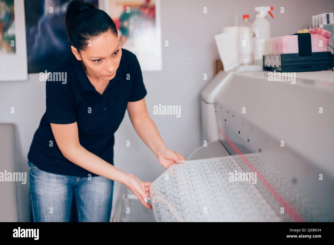 Young woman technician working on plotter and cutter machine in printing centar Stock Photo