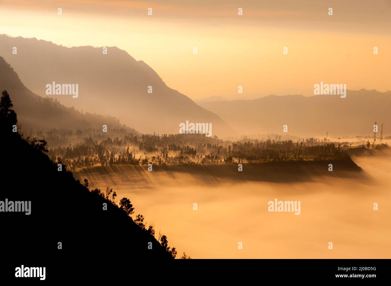 Steep black mountain silhouette in front of thick Fog Sheet Stock Photo