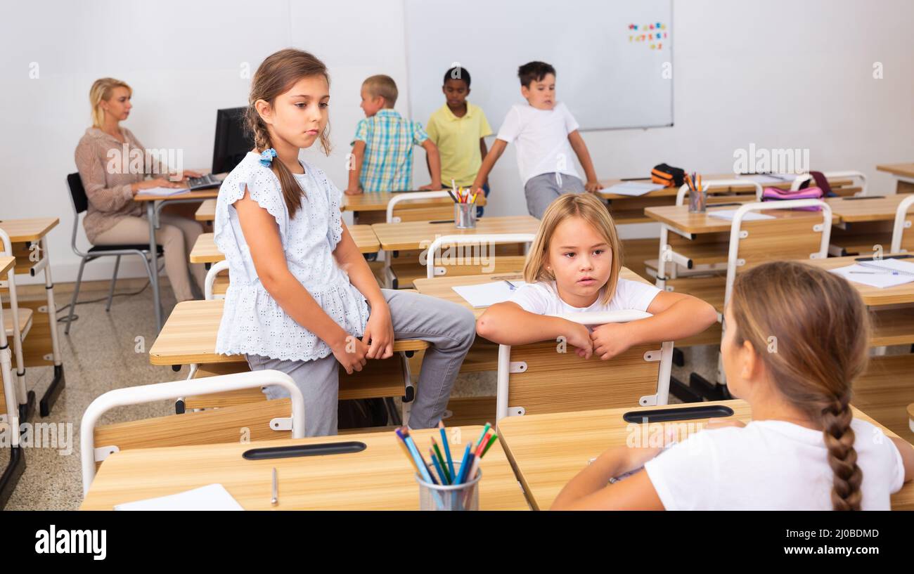 Happy preteen schoolchildren communicating during recess in classroom Stock Photo