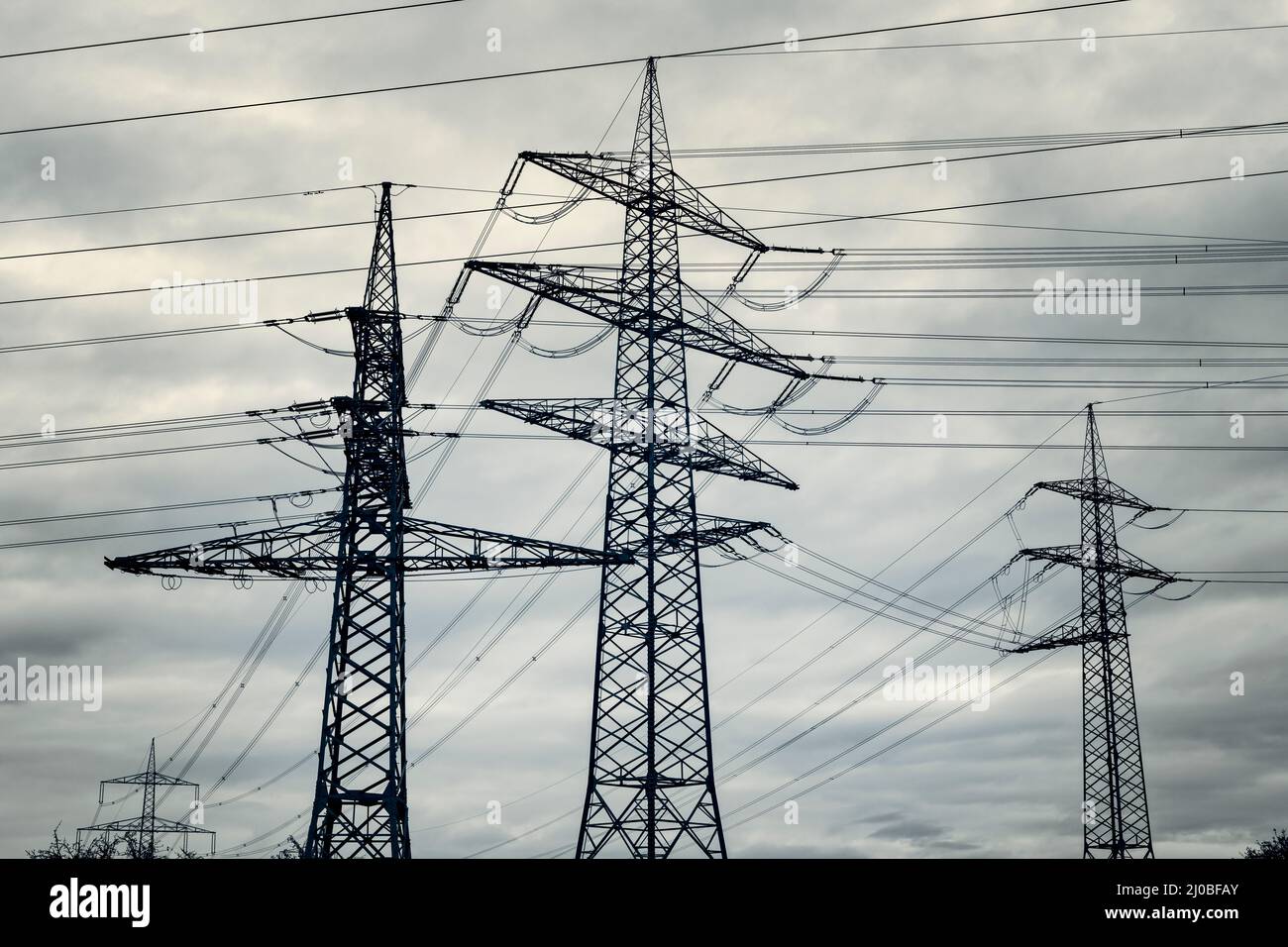 Power pylons of overhead power line against dramatic sky Stock Photo