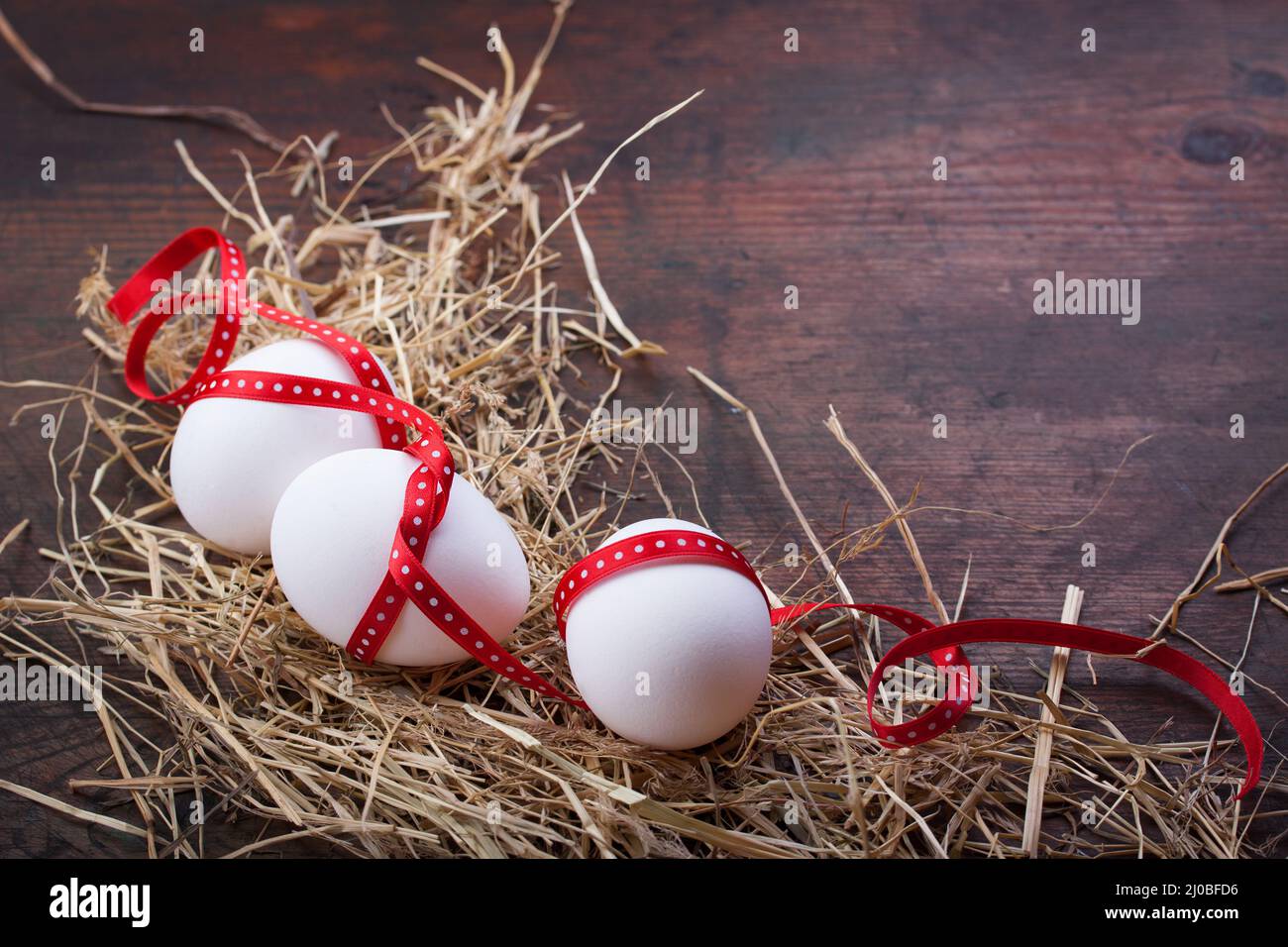 Eggs with a red ribbon on the hay for easter Stock Photo - Alamy