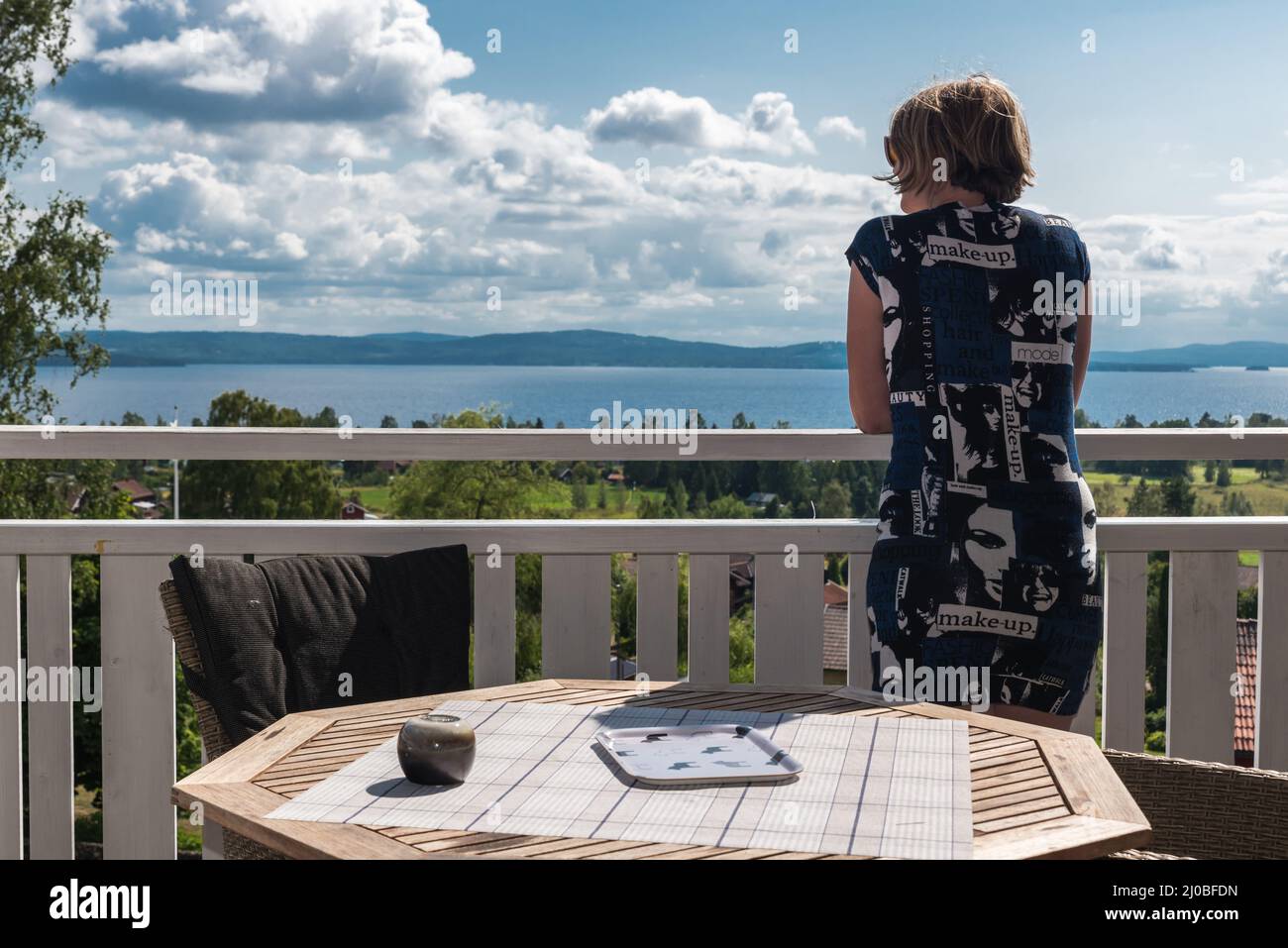 Segersta, Halsingland - Sweden - 08 04 2019   Attractive woman in summer dress posing at a terrace of a Swedish Bed and Breakfast with a view over the Stock Photo