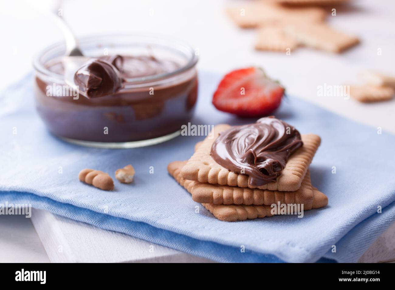 Chocolate sweet melting nougat cream on cookies with strawberries on a white plate Stock Photo
