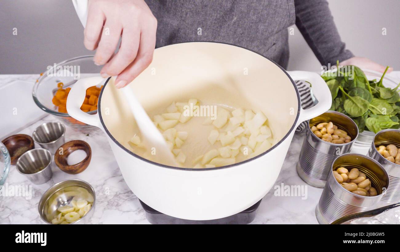 Cooking vegetarian white bean soup in cast iron dutch oven Stock Photo
