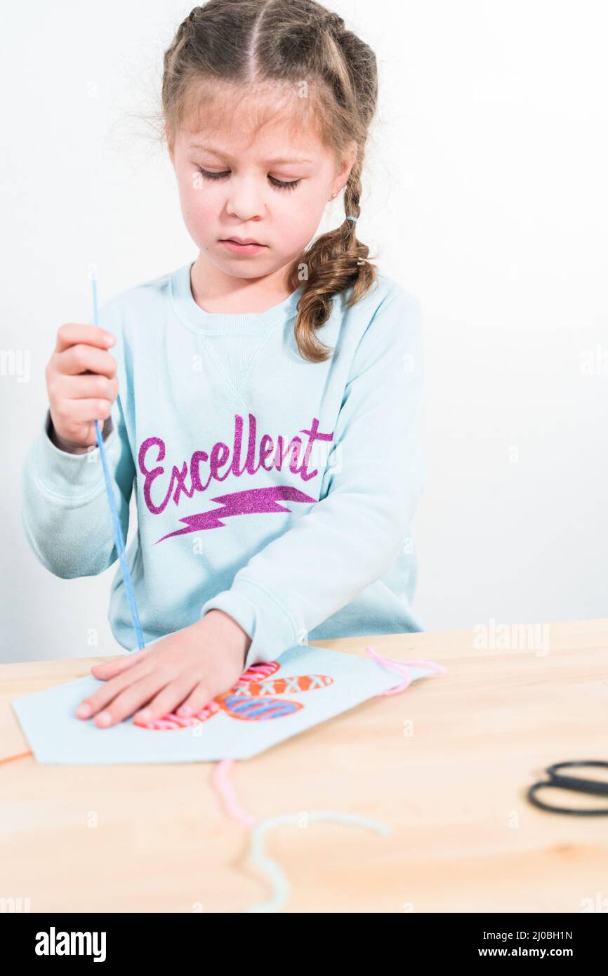 Little girl learning how to sew with sewing craft kit for kids Stock