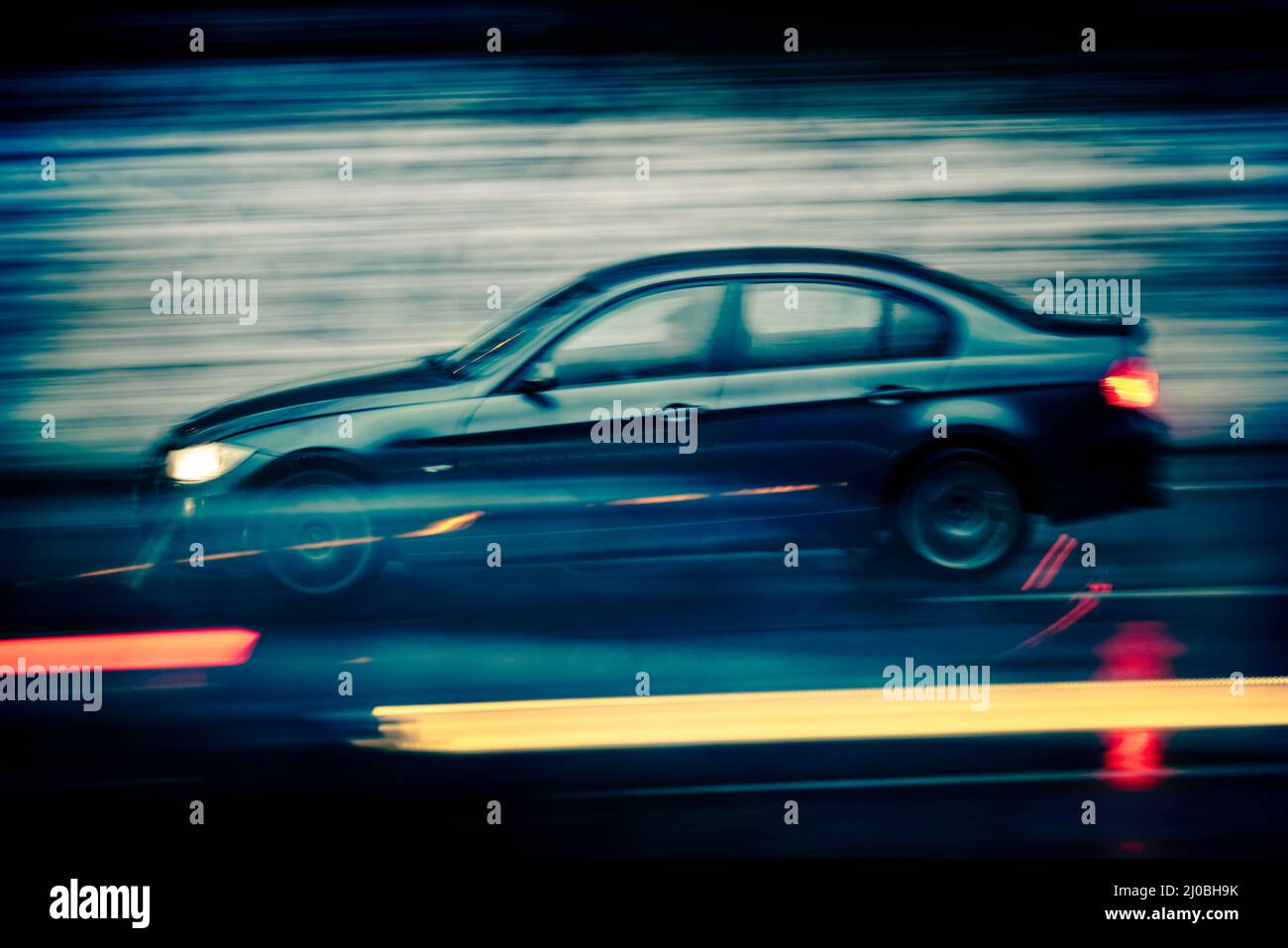 Car driving at high speed on a country road at dusk Stock Photo