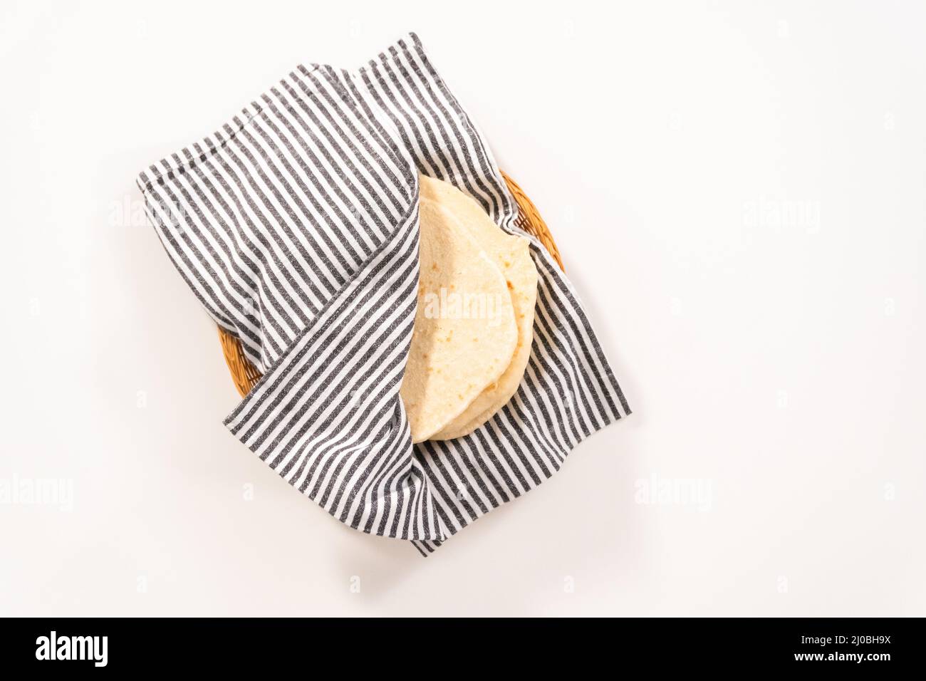 Flat lay. Stack of freshly baked flatbread wrapped in a kitchen towel ...