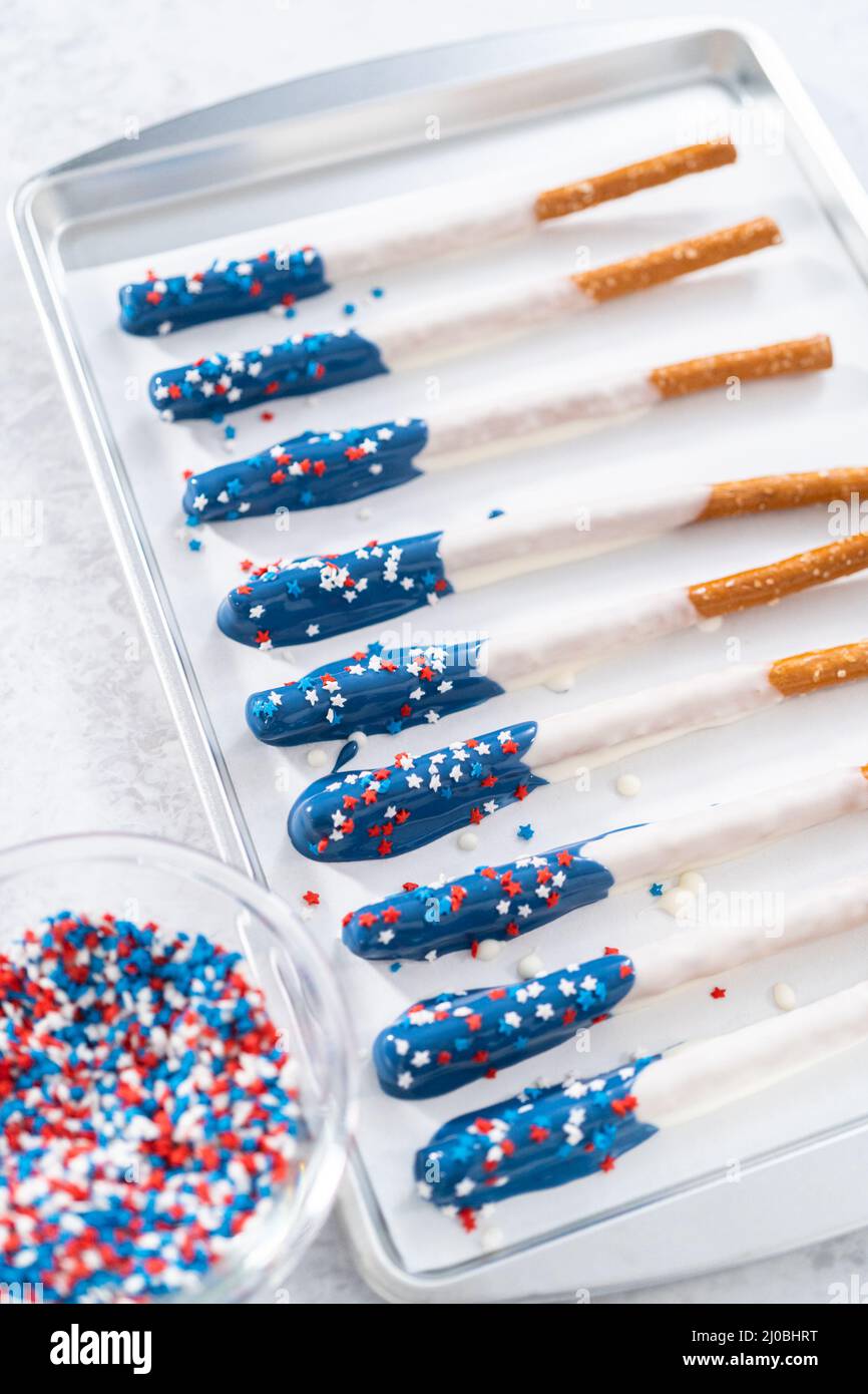 Dipping pretzel rods into the melted chocolate to prepare chocolate ...