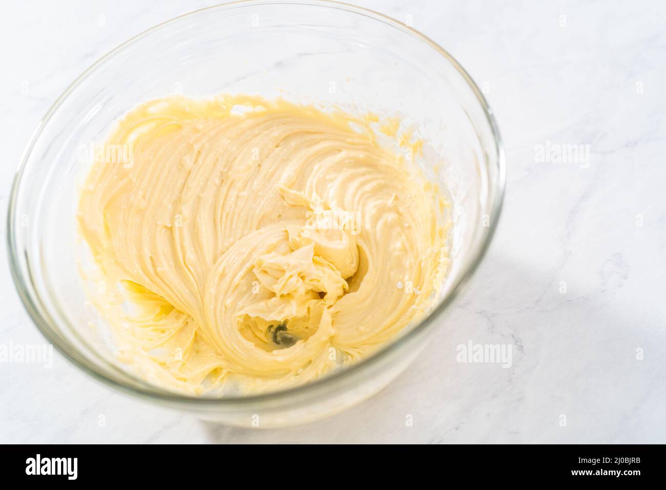 Mixing ingredients in a large glass mixing bowl to make the cream