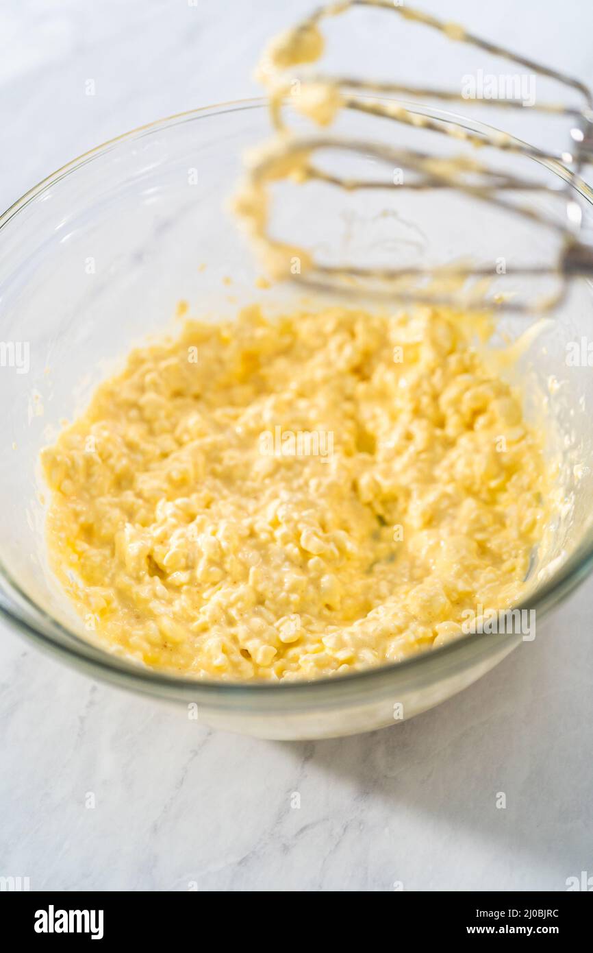 Mixing ingredients in a large glass mixing bowl to make the cream