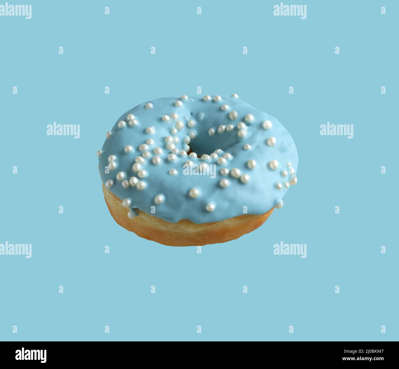 Donuts covered with pale blue icing and sprinkled with pearl sugar beads on a light blue background. Closeup Stock Photo